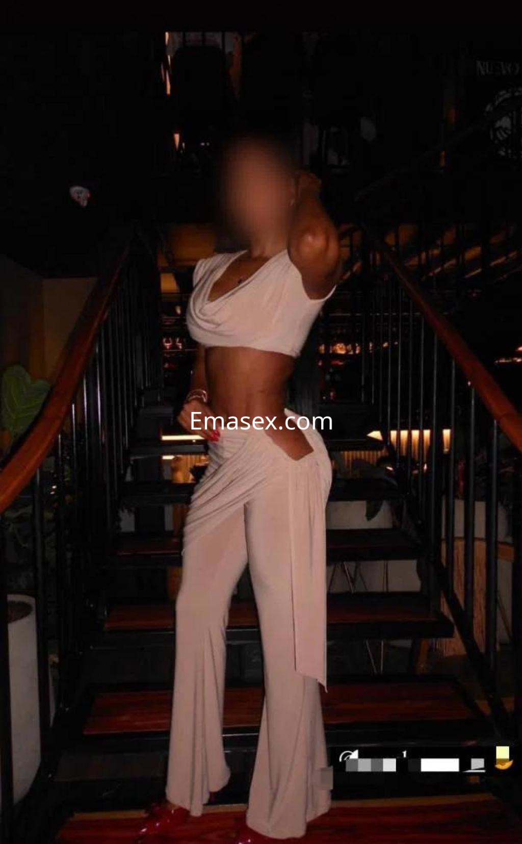 Escort en Palma de Mallorca, con un conjunto beige que destaca su figura, posando en una escalera elegante.