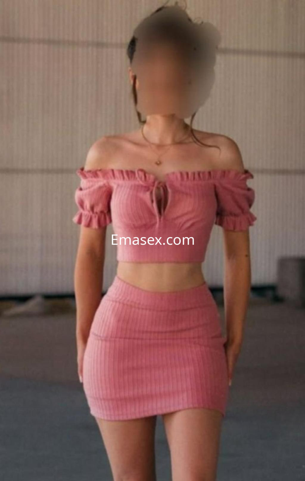 Escort en Zaragoza, posando en un entorno urbano con un conjunto rosa de dos piezas que realza su figura.