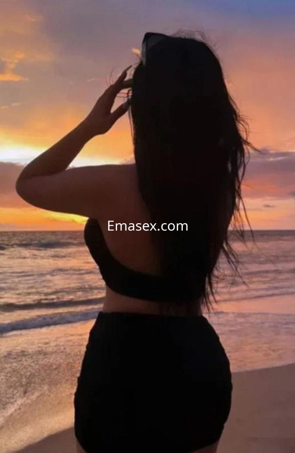 Puta de espaldas con cabello largo y oscuro, luciendo un bikini negro en la playa de Logroño al atardecer.
