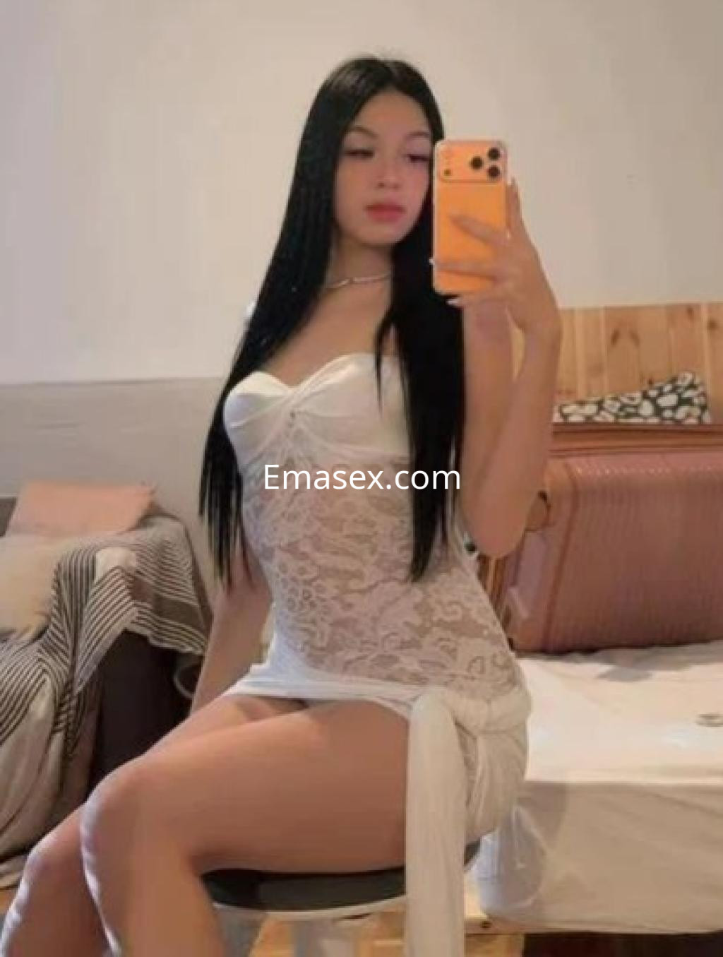 Puta con cabello largo y lacio, vistiendo una prenda de encaje blanca, sentada en una silla en León.