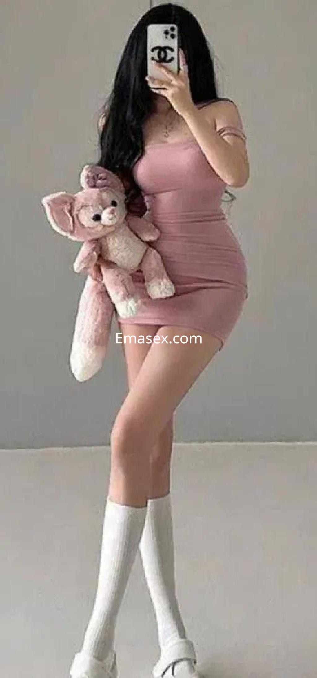 Escort en Tenerife con vestido ajustado rosa, sosteniendo un peluche, y medias altas blancas.