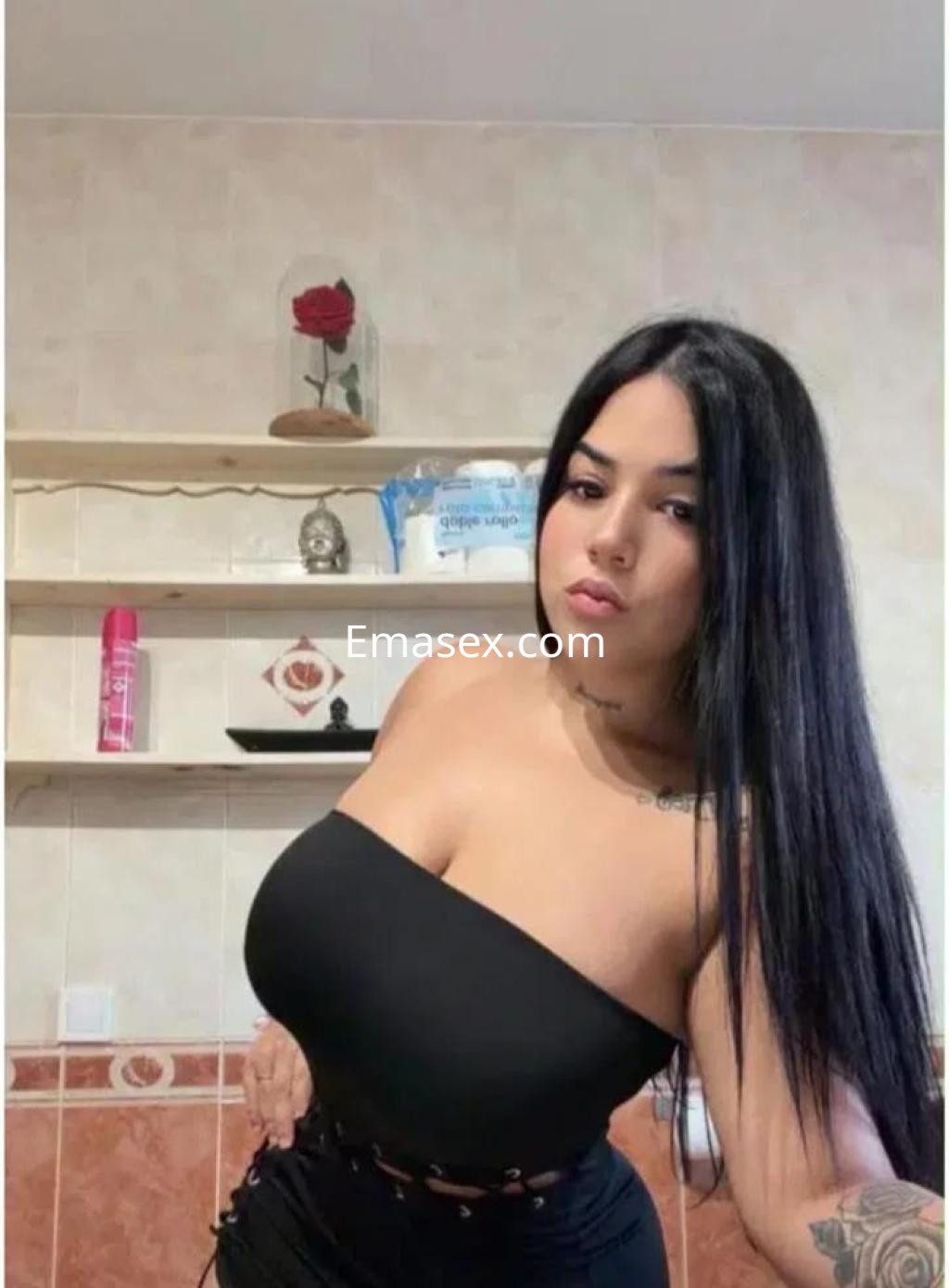 Puta de cabello largo y oscuro, vestida con top negro, posando en un baño en Toledo.
