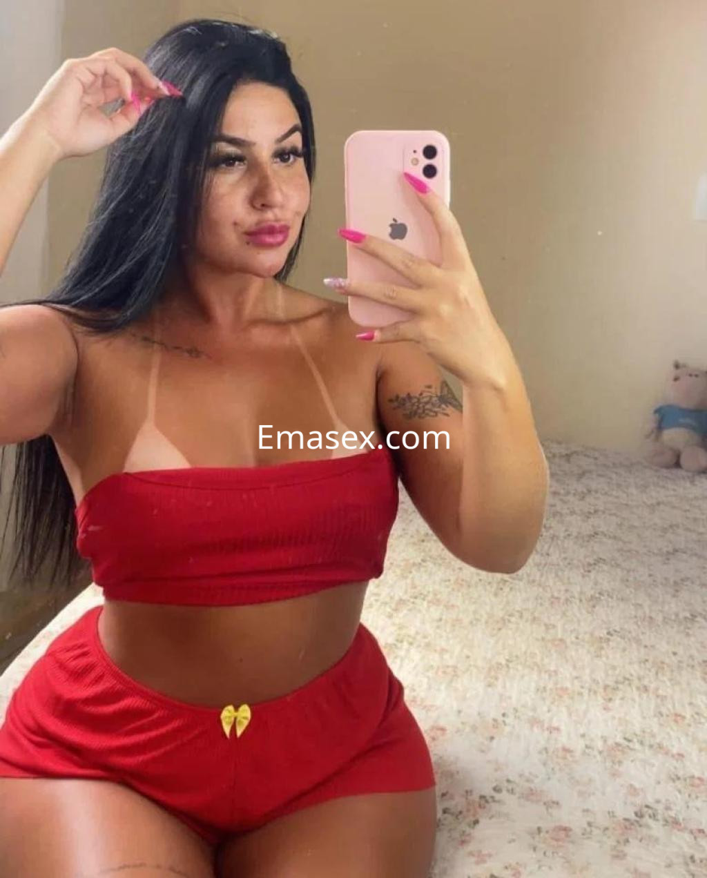 Escort en Toledo tomando una selfie, con cabello largo y lacio, vistiendo un conjunto rojo de top y shorts.