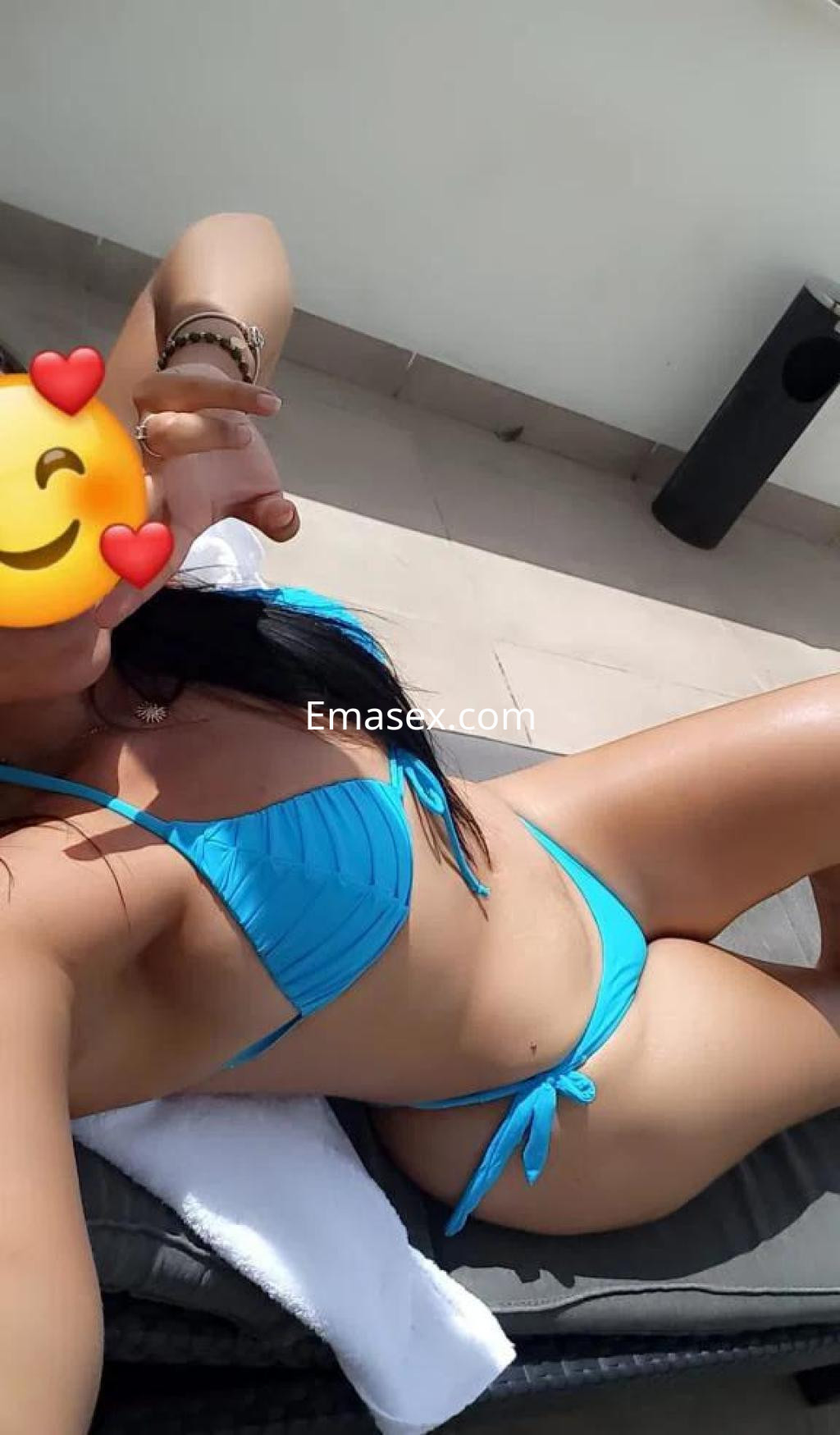 Escort en Pontevedra, descansando al sol en una silla de playa, luciendo un bikini azul y con el pelo largo.