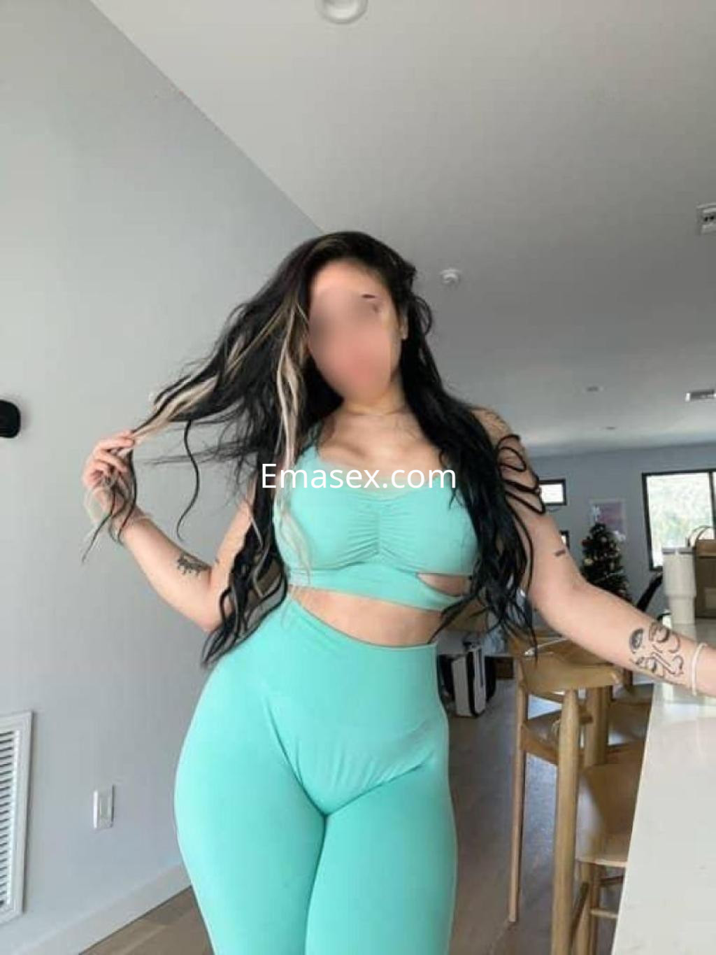 Escort en Cáceres viste un conjunto deportivo azul claro, mostrando su figura mientras juega con su cabello.