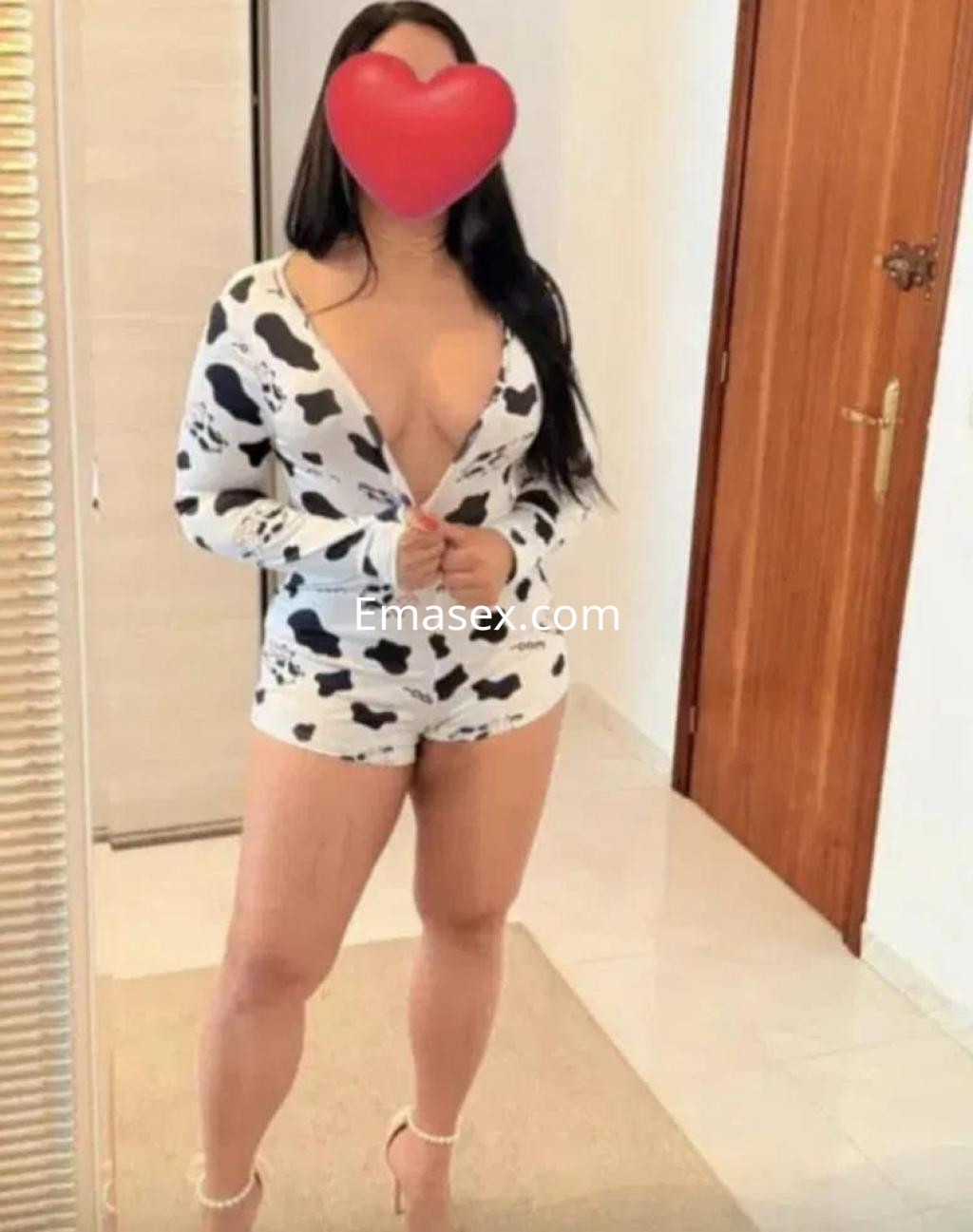 Escort en Albacete viste un conjunto de lencería de vaca, con escote pronunciado y tacones altos.
