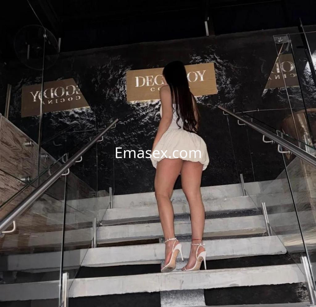 Puta de cabello largo y oscuro, viste un vestido corto y tacones altos, subiendo escaleras en Cádiz.