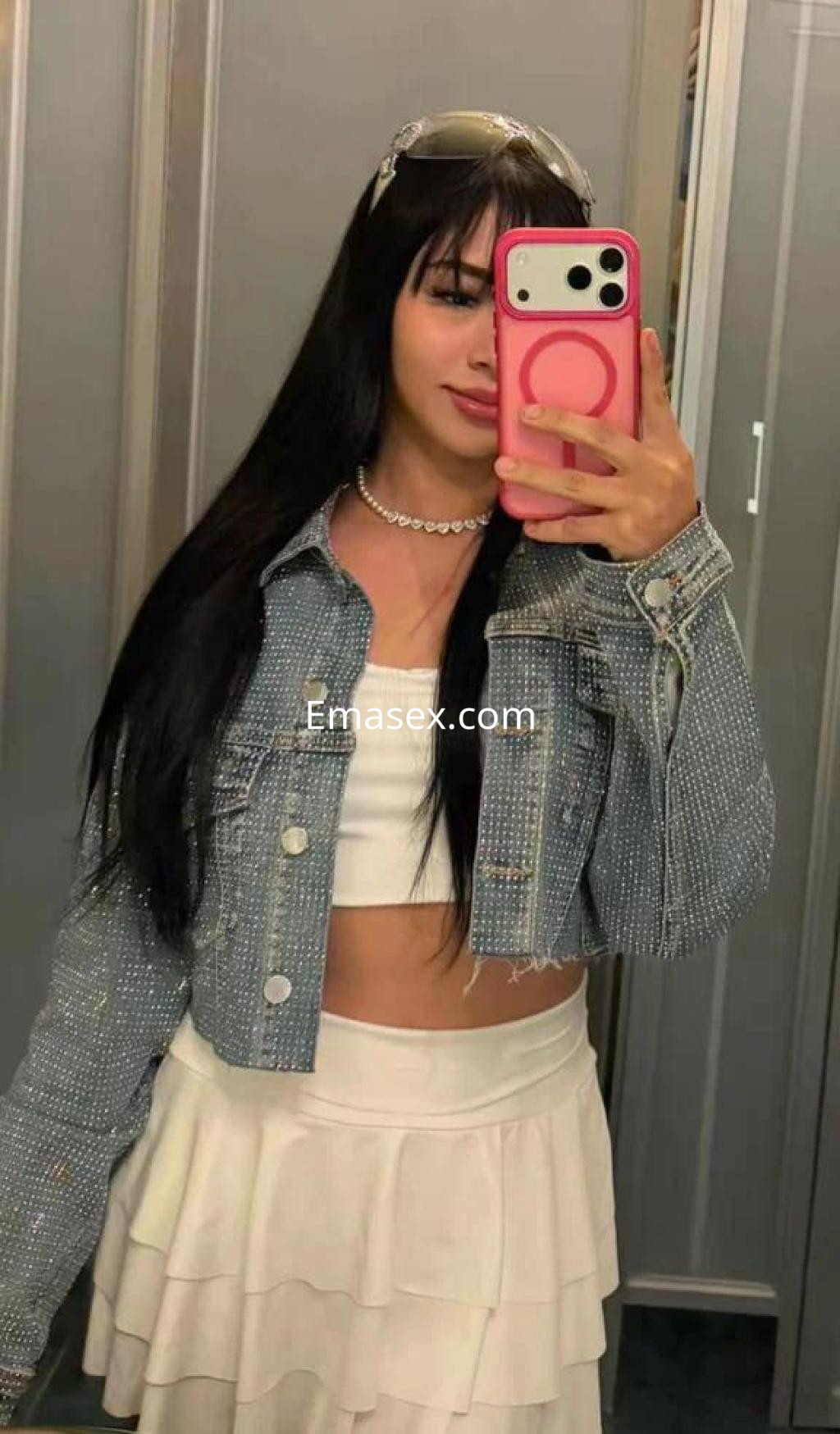 La puta en Salamanca viste una chaqueta de mezclilla brillante y una falda corta blanca, con cabello largo y lacio.