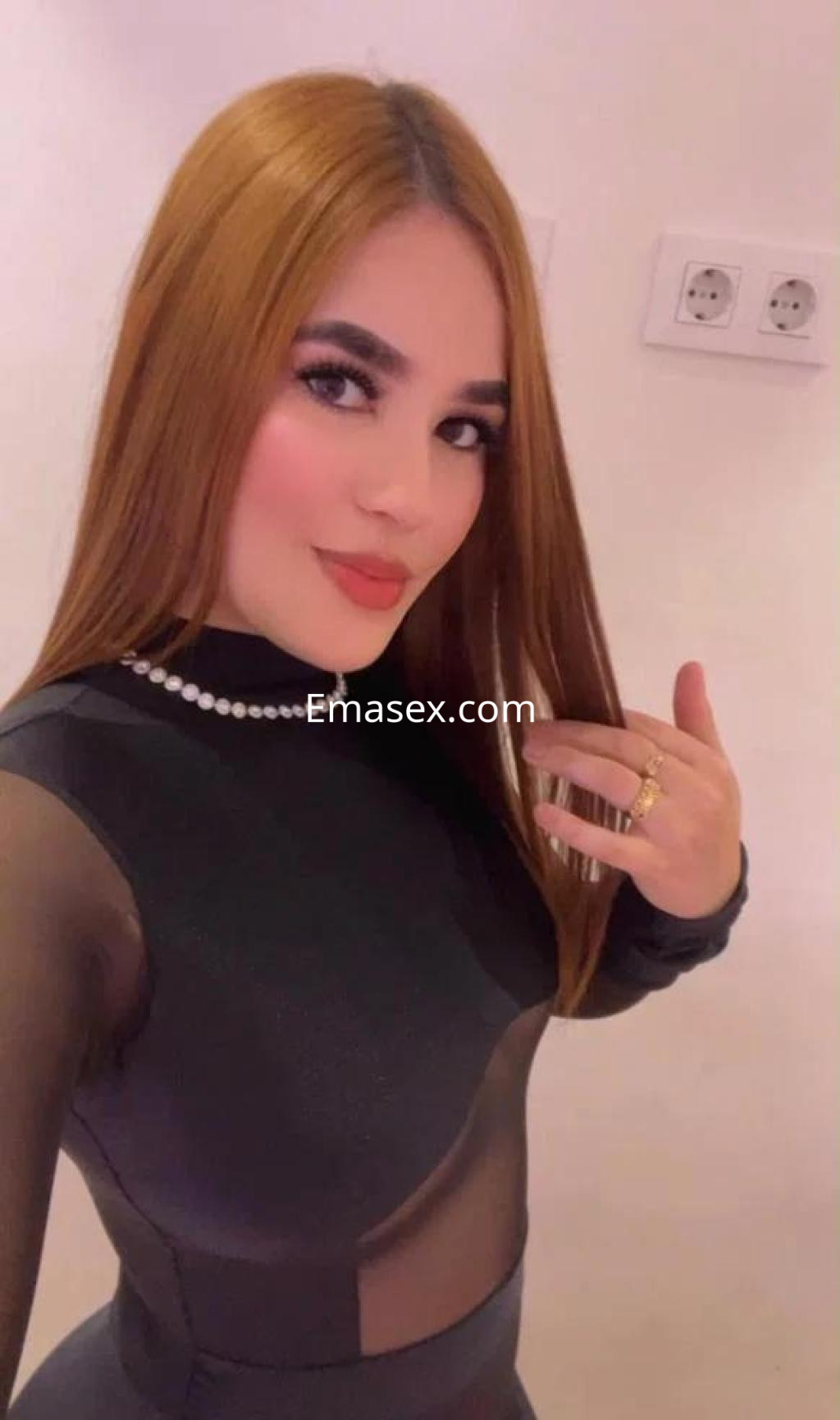 Escort en Alicante con cabello largo y lacio, vistiendo un top negro transparente y joyería elegante.