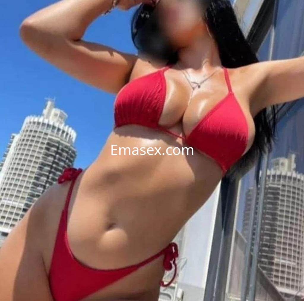 La puta posa en un bikini rojo, con cabello largo y lacio, frente a un paisaje urbano en Santander.