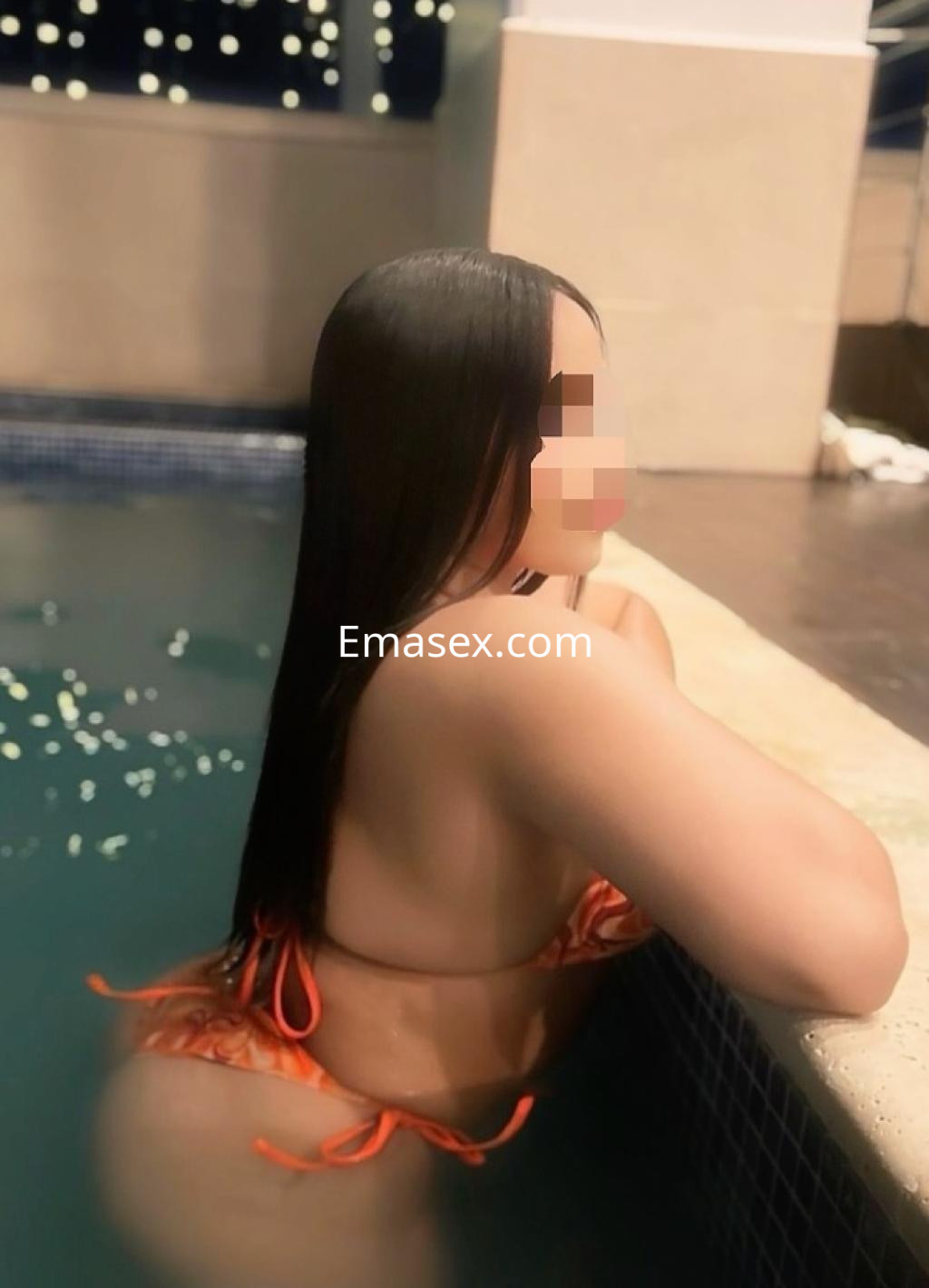 Puta de cabello largo y lacio, con bikini naranja, posando de perfil en una piscina en Vitoria.