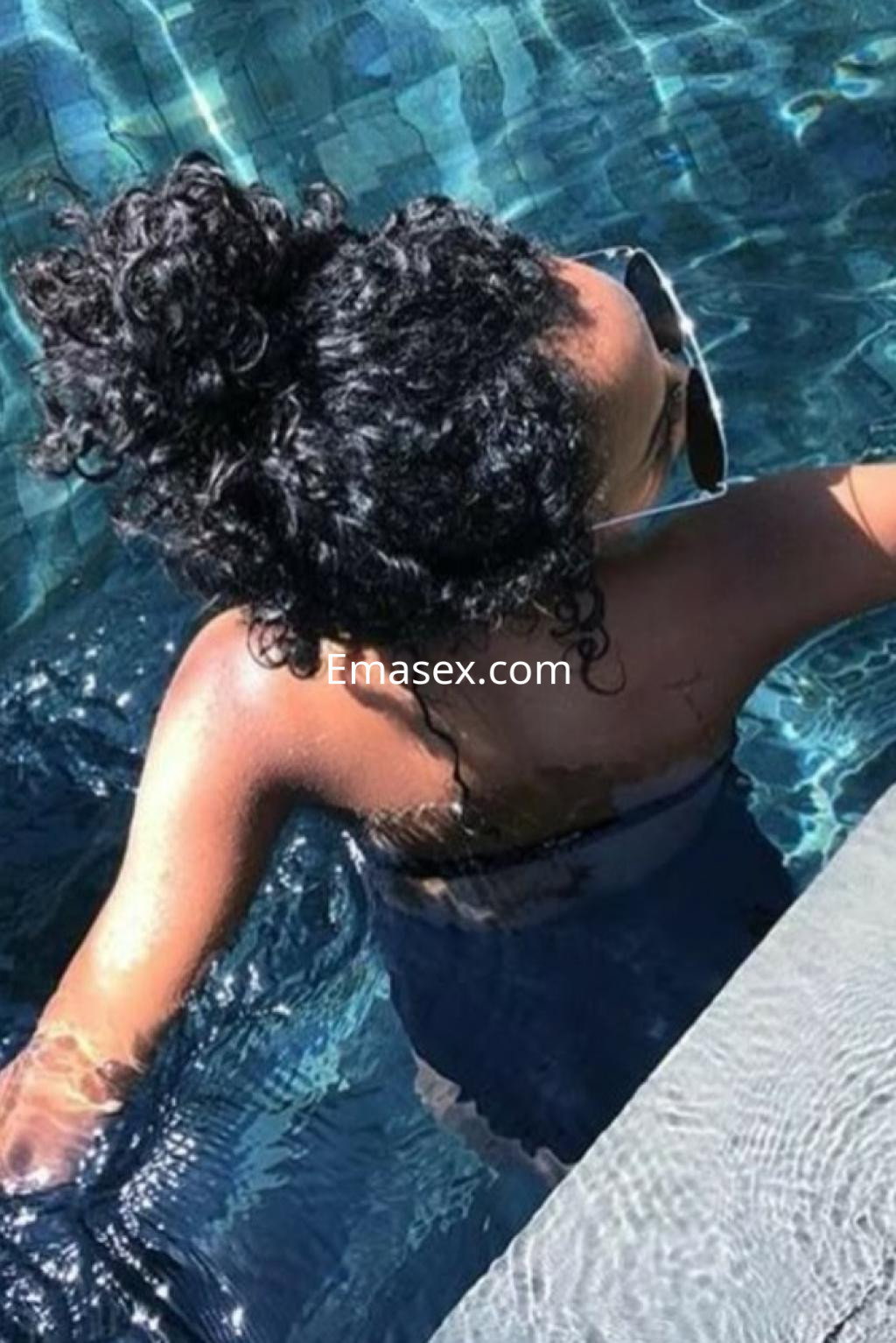 Escort en Logroño, con cabello rizado y recogido, disfrutando de un momento en la piscina.