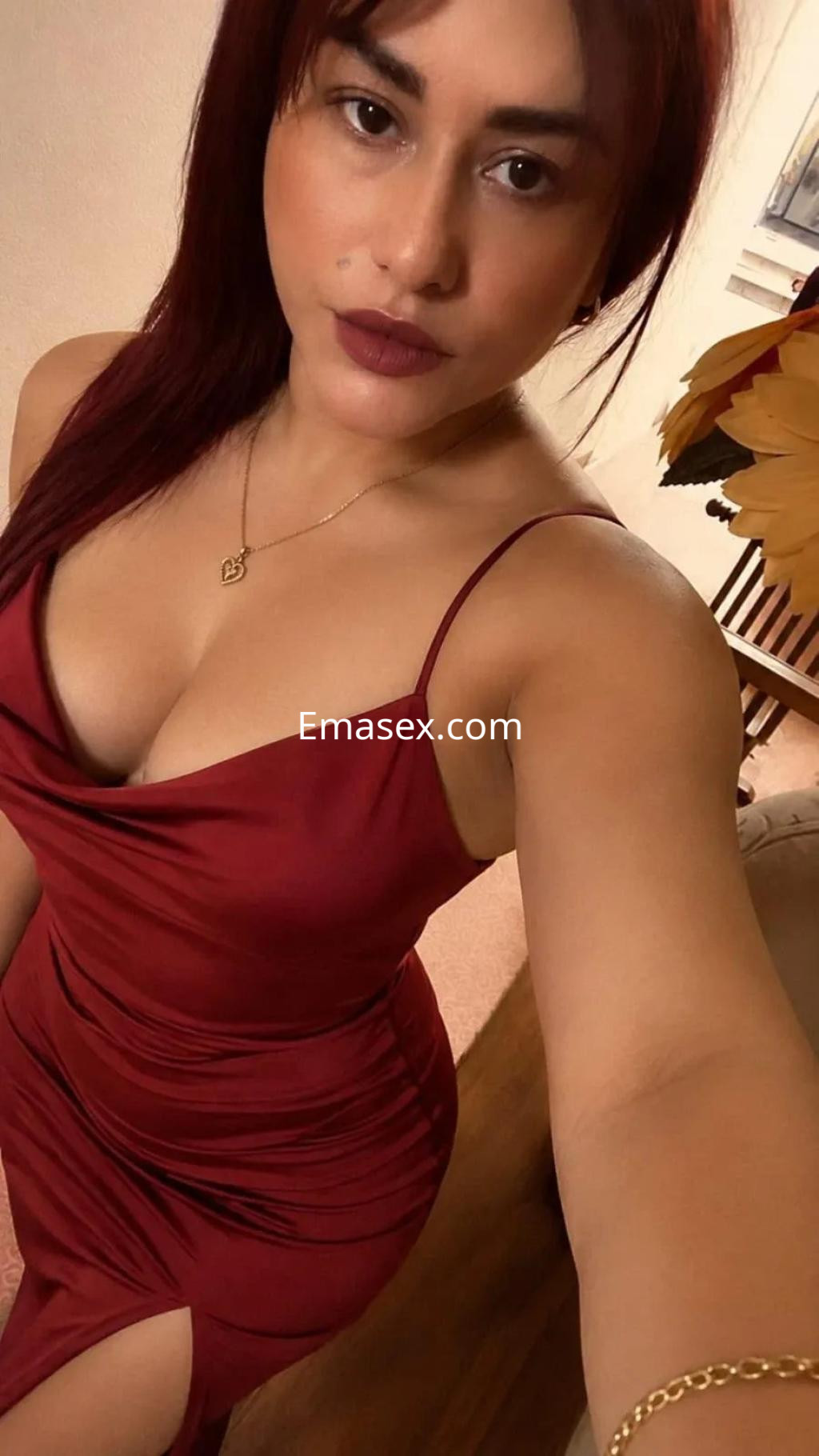 Puta con vestido rojo ajustado y escote, posando en un ambiente acogedor de Santander.