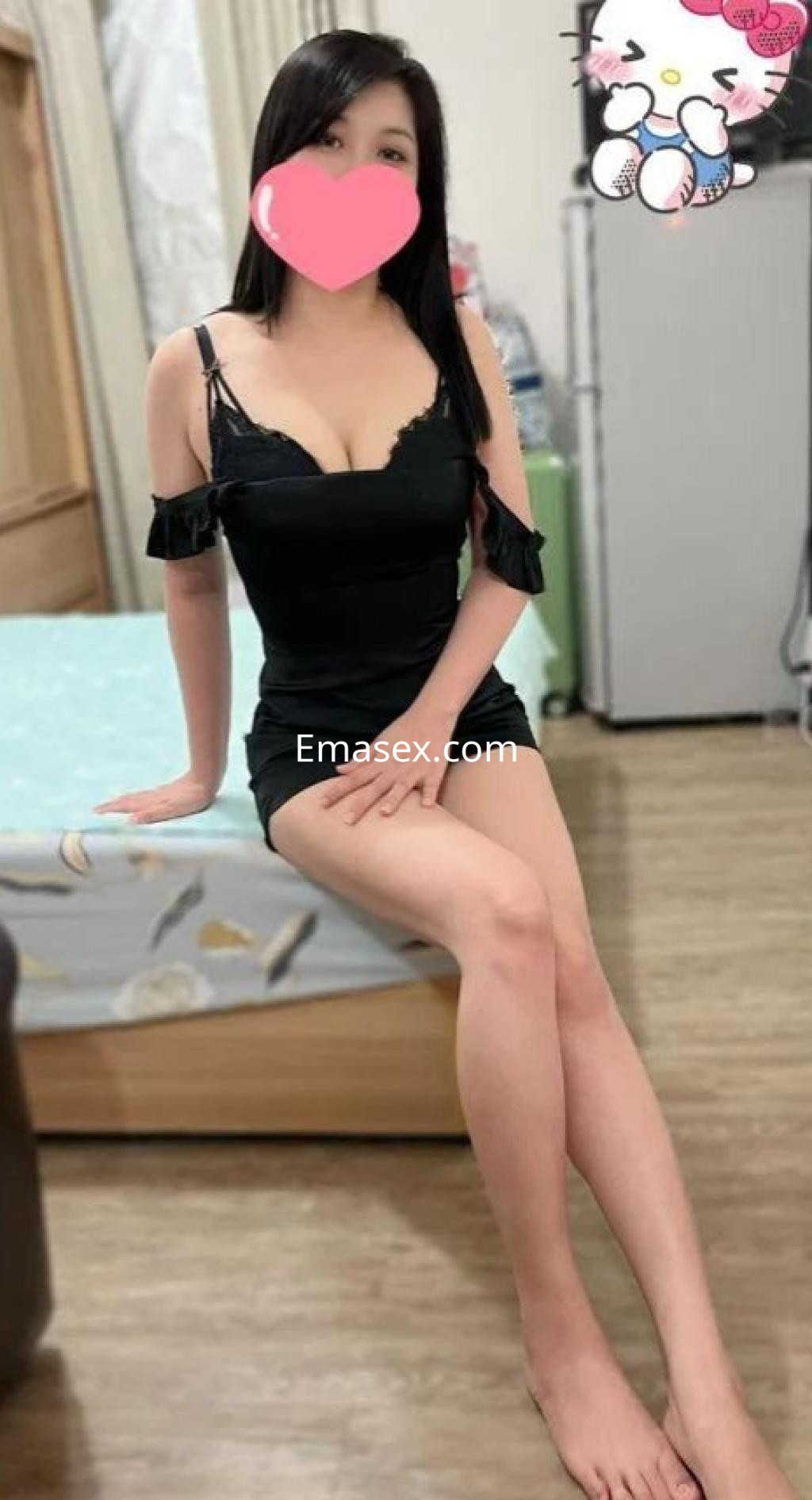 La puta lleva un vestido negro sin mangas, sentada en una cama con una pose coqueta en Madrid.
