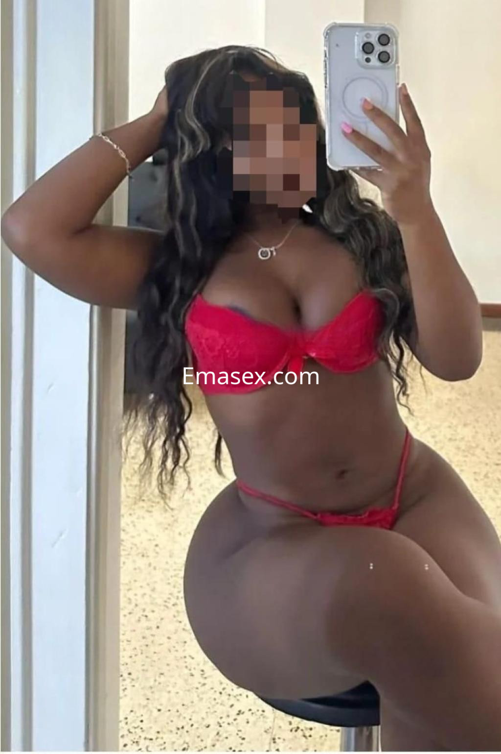 Escort en Alicante posando en lencería roja, con cabello largo y ondulado, sentada en un taburete.