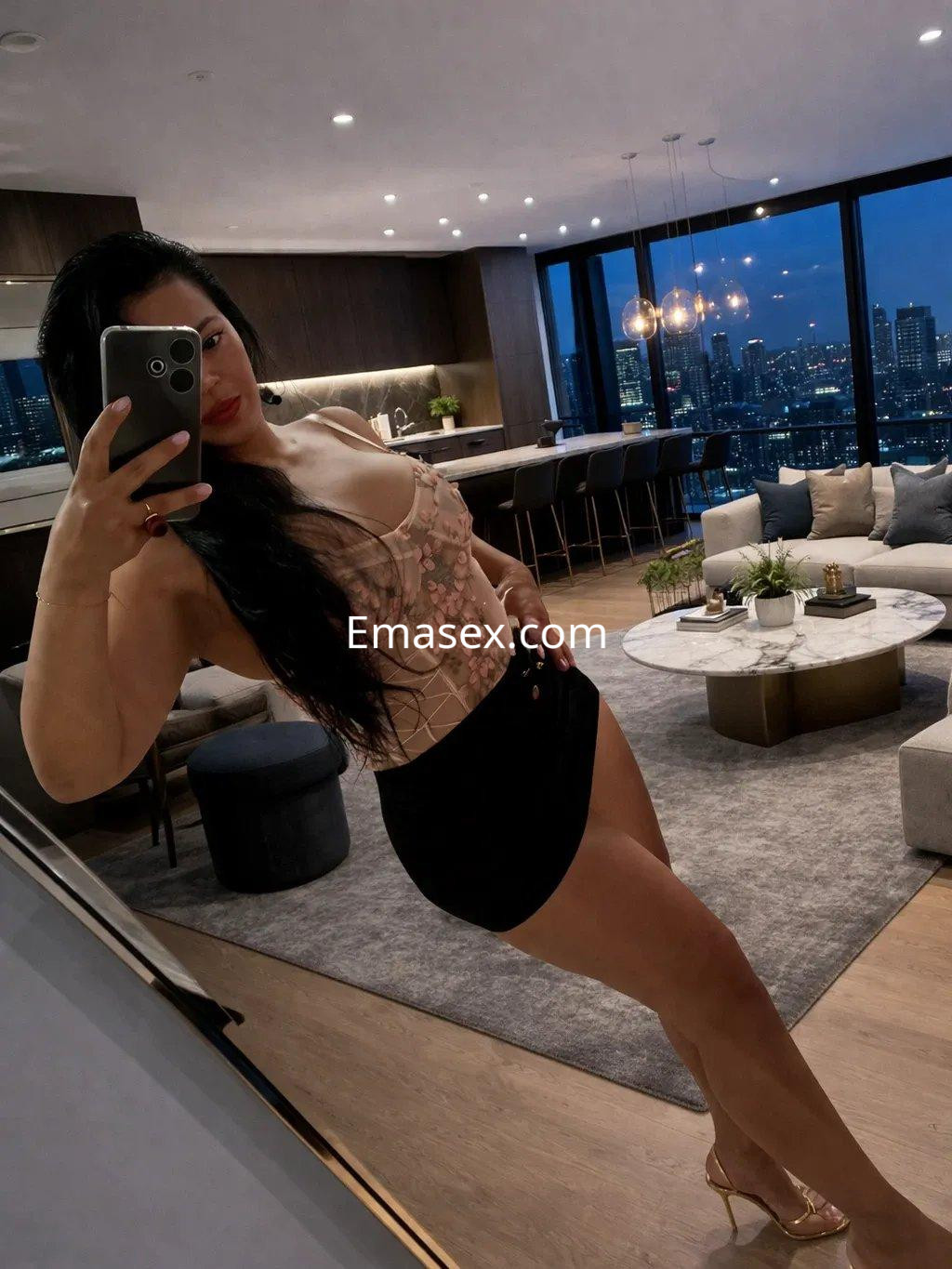 La escort en Palma de Mallorca se muestra con un vestido ajustado y tacones, posando en un elegante salón moderno.