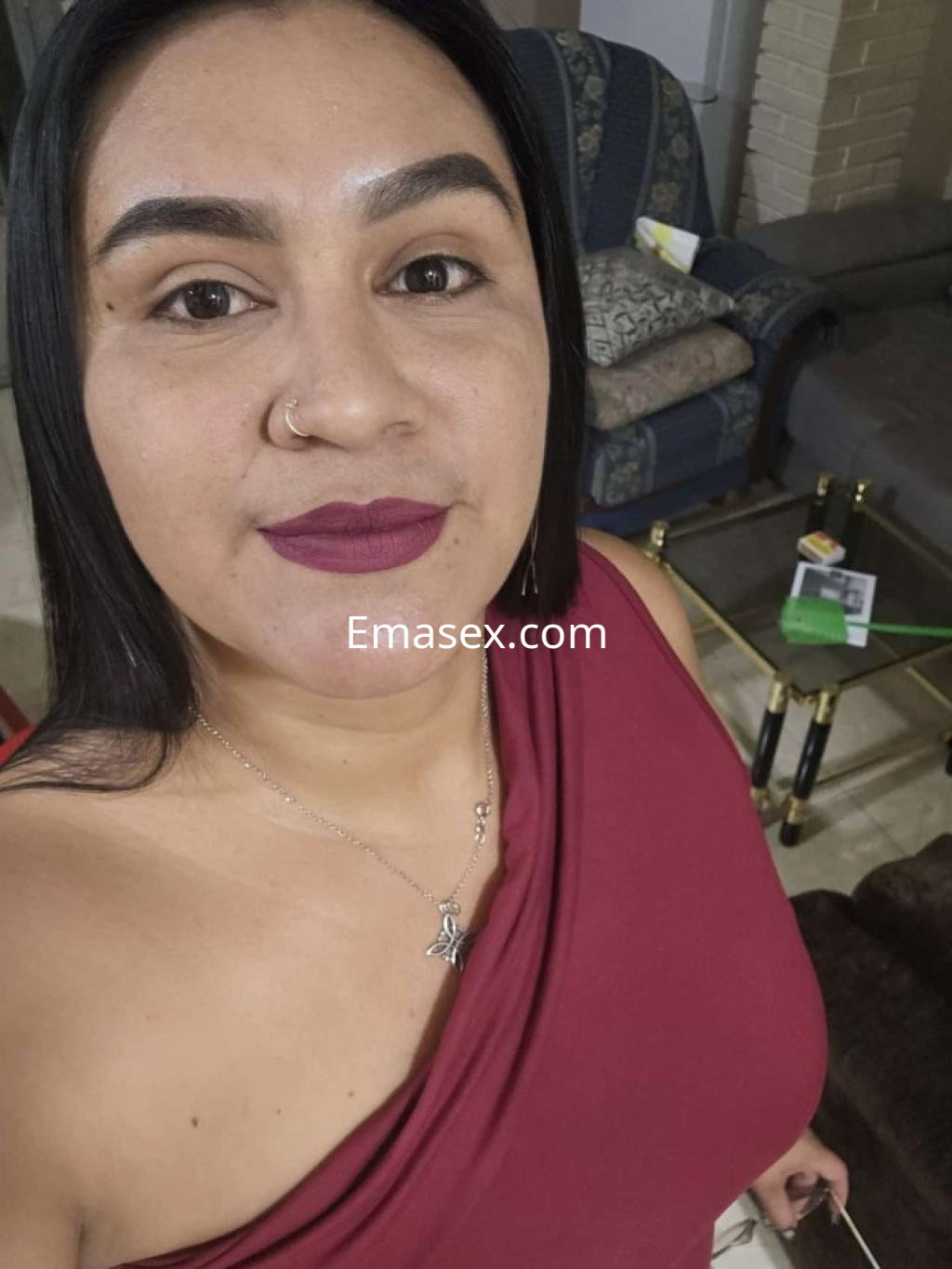 Escort en Castellón con blusa de un solo hombro en tono burdeos, labios en color intenso y cabello lacio.