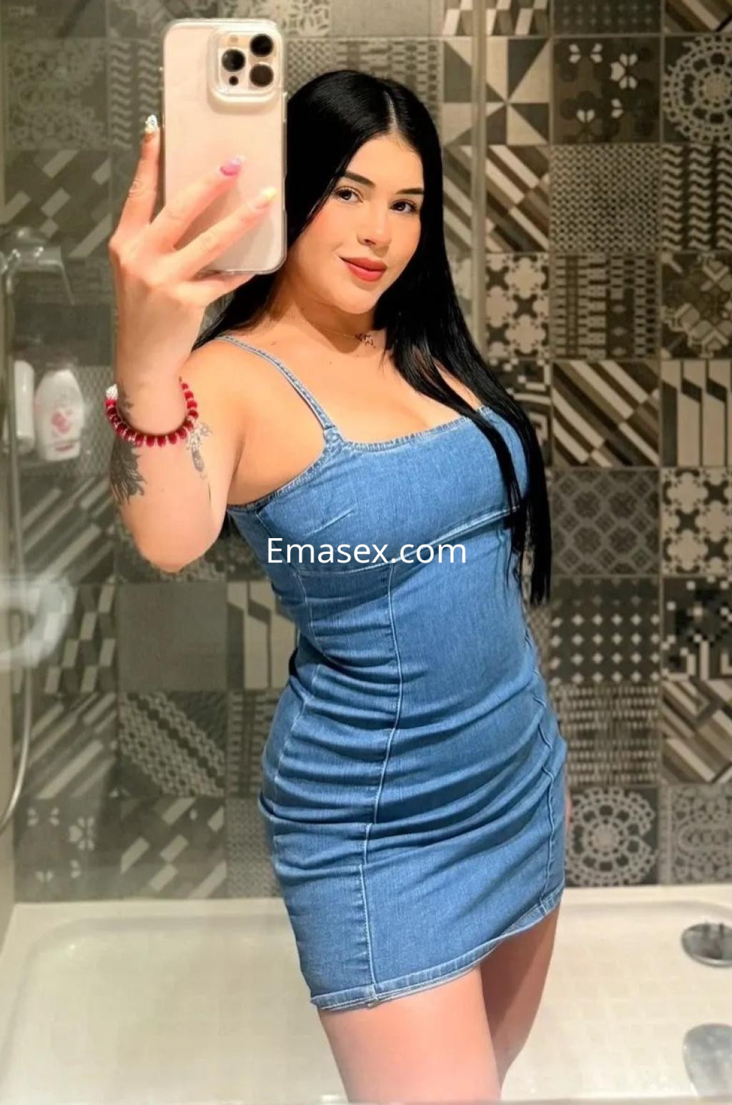 Escort de cabello lacio y negro, viste un vestido de mezclilla ajustado, posando en un baño moderno en Oviedo.