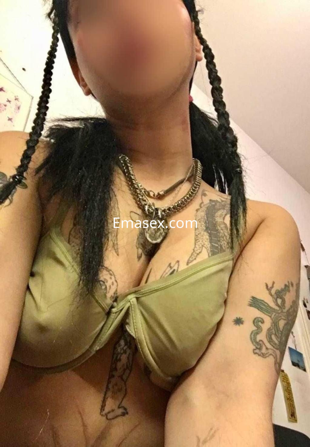 La puta en Barcelona luce un sujetador verde y joyería, con cabello trenzado y varios tatuajes visibles.
