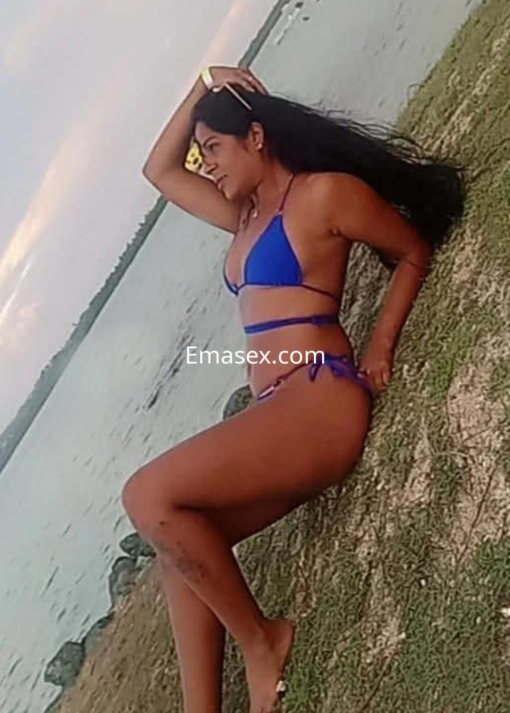 Puta en Logroño, con cabello largo y oscuro, luciendo un bikini azul mientras posa en la orilla de un lago.