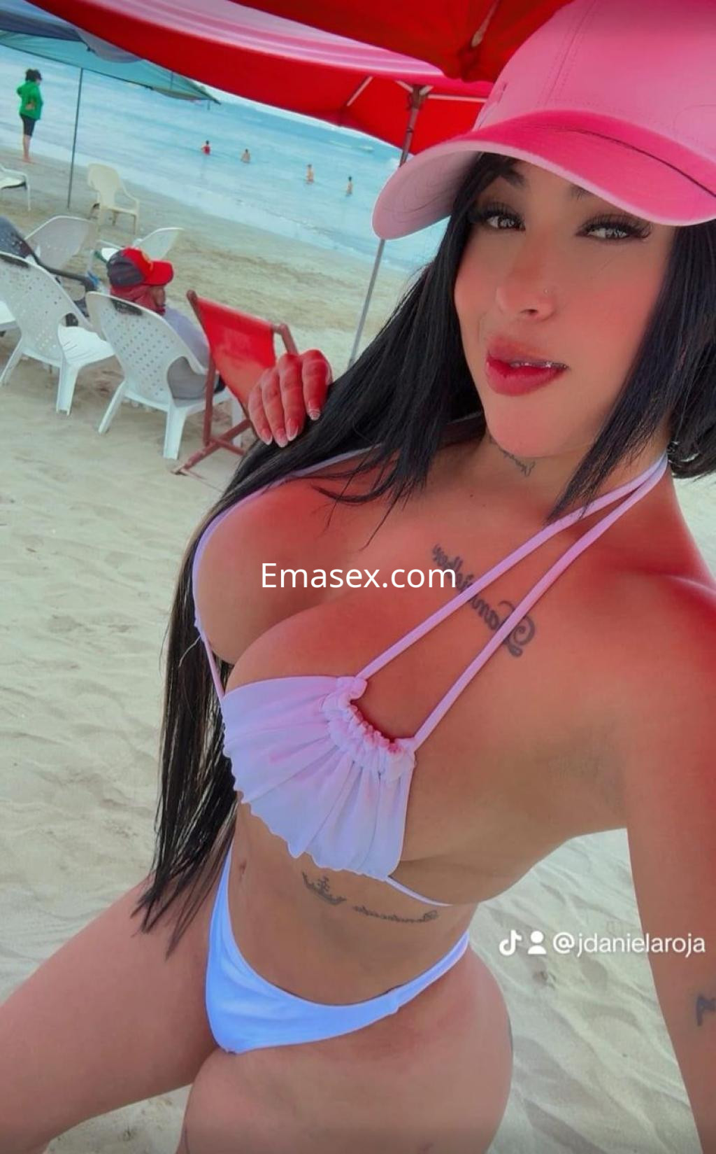 Puta en Vitoria con un bikini blanco y gorra rosa, posando en la playa con cabello largo y lacio.