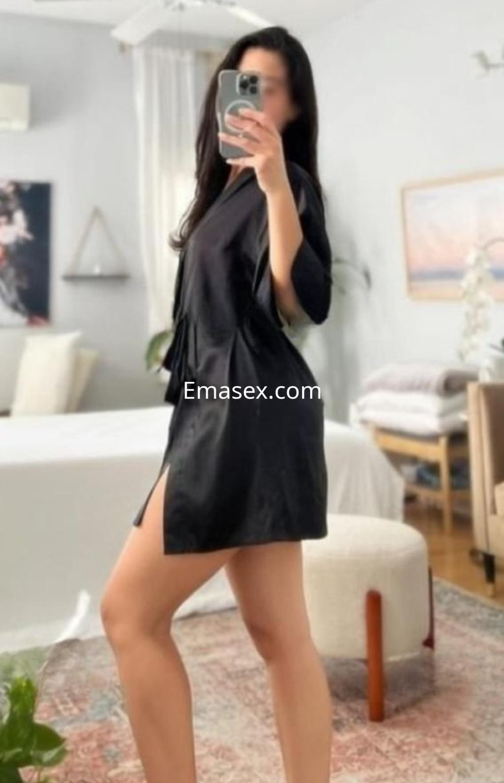 La escort de Castellón se muestra de perfil con un albornoz negro, destacando una pose elegante en un ambiente acogedor.