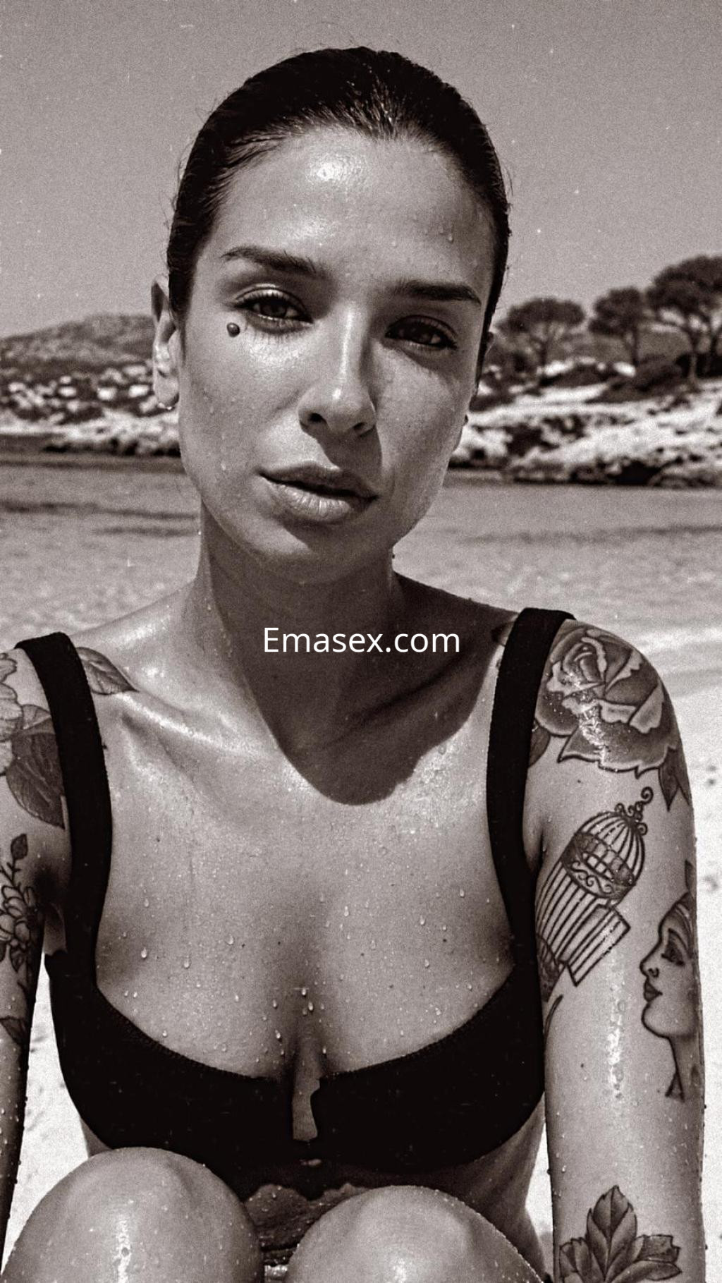 Escort en Santander luce un bikini negro y muestra sus tatuajes mientras posa en la playa.