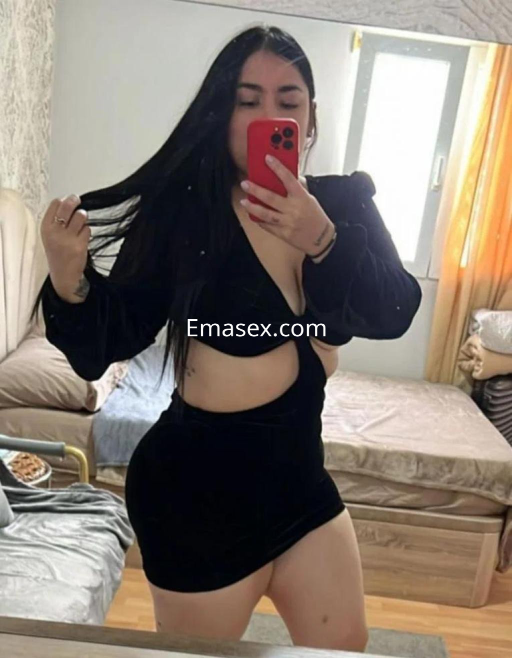 Escort en Pamplona posando frente a un espejo, con vestido negro ajustado y cabello largo, mostrando una postura seductora.