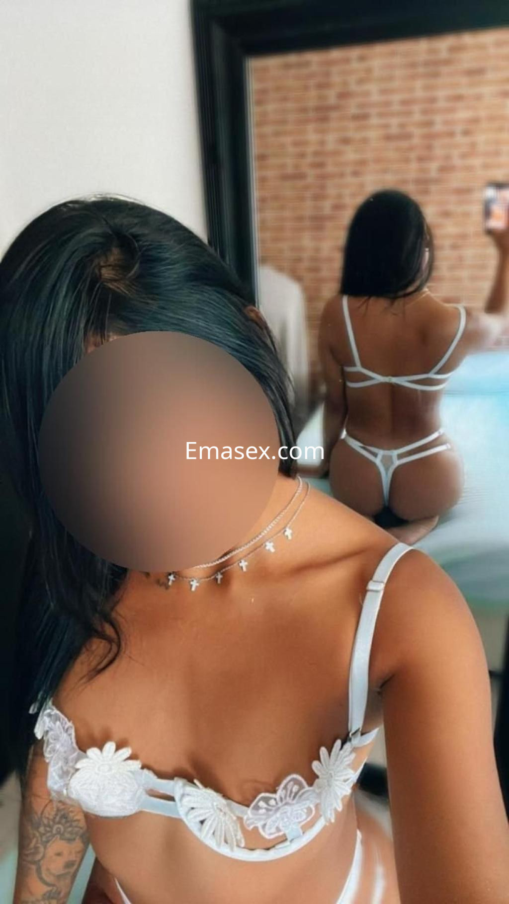 Escort en Alicante posando de espaldas con lencería blanca, mostrando su figura y reflejo en el espejo.