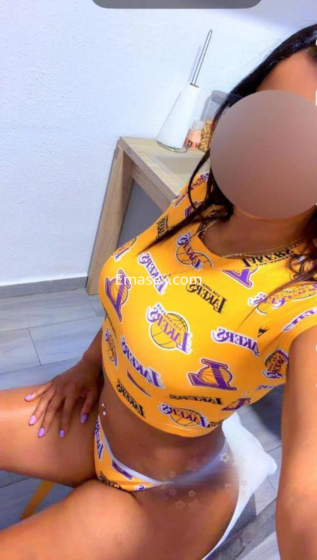 Escort en Valencia vistiendo un conjunto amarillo con estampado deportivo, sentada de forma relajada.