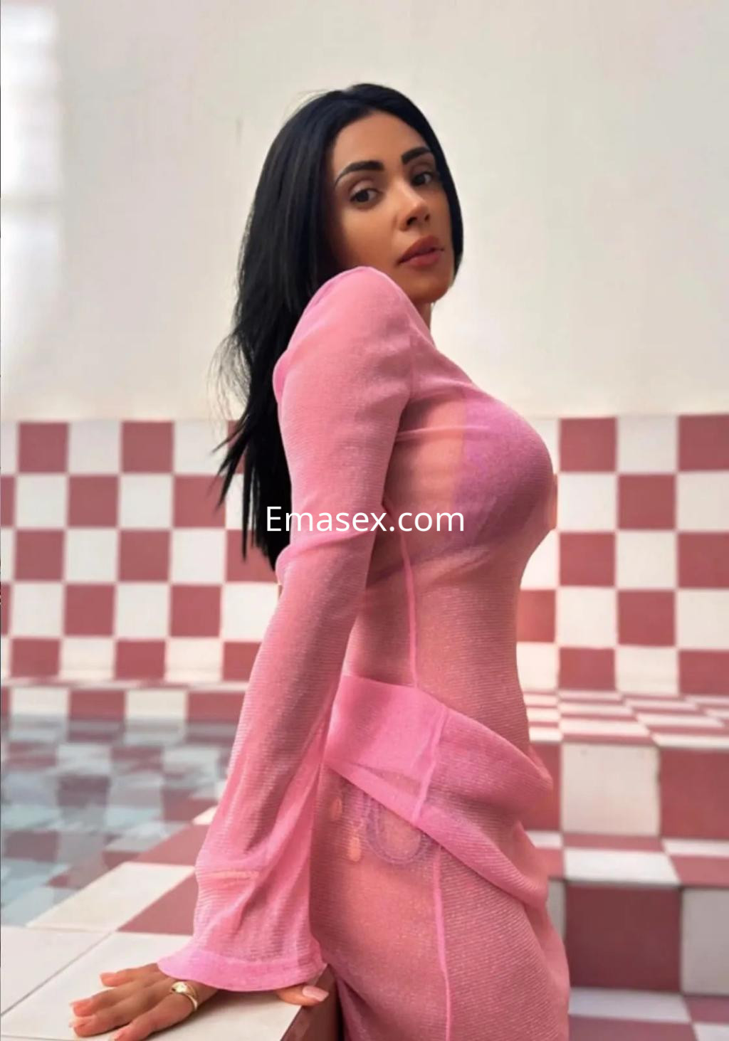 La puta en Coruña viste un vestido rosa translúcido que se ajusta a su figura, con cabello lacio y suelto.