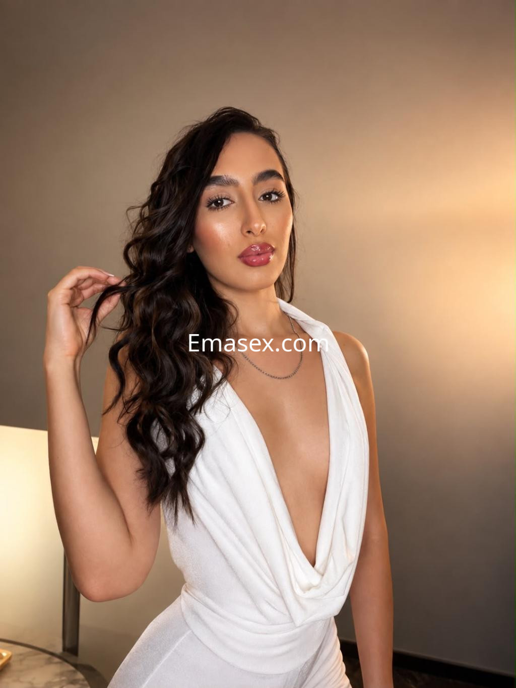 Escort en Bilbao con cabello largo y ondulado, vestida con un elegante traje blanco que resalta su figura.