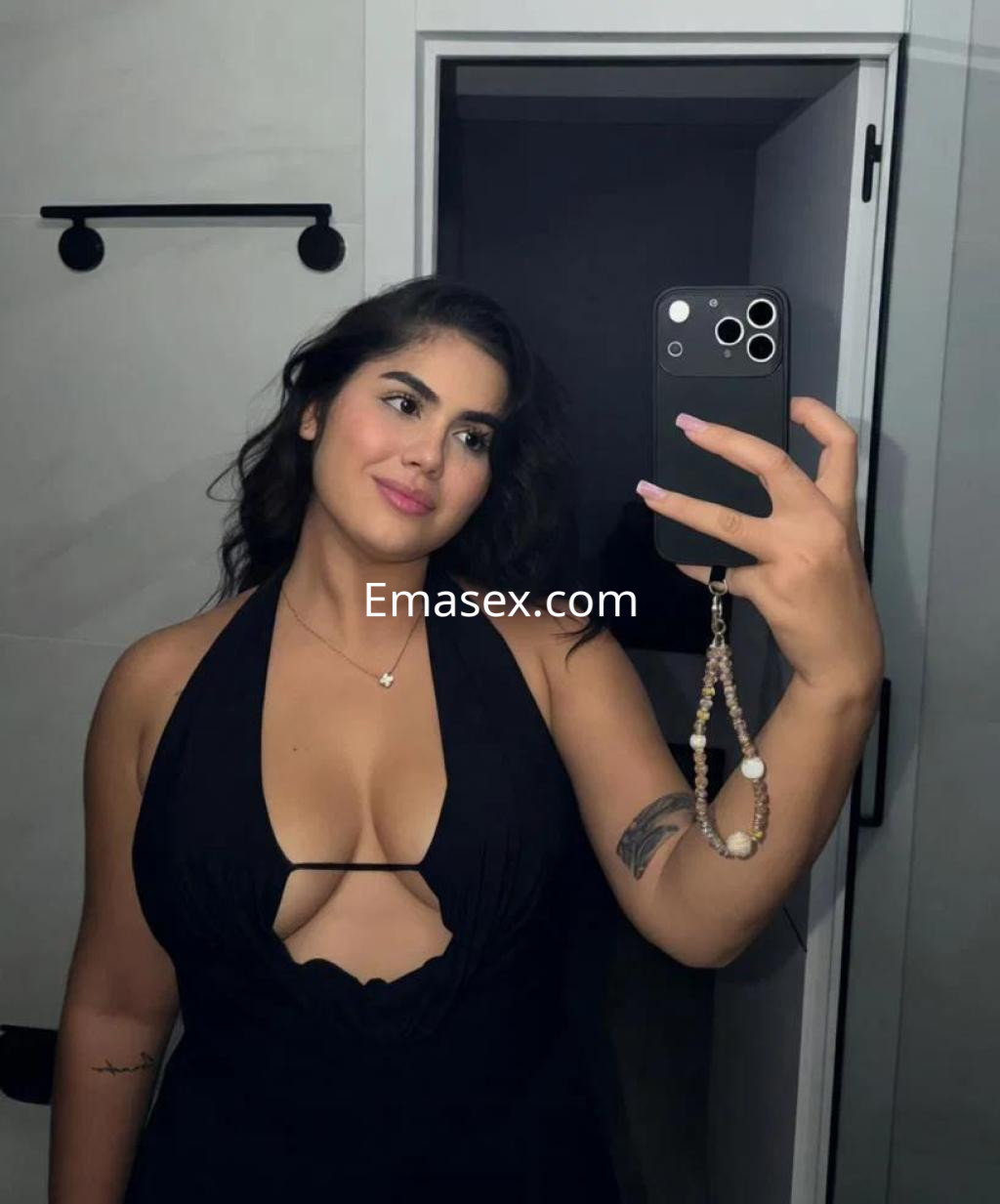Escort en Girona con cabello oscuro y ondulado, vestida con un vestido negro que tiene un escote pronunciado.