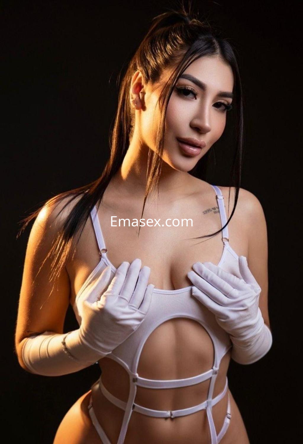 Puta en Barcelona viste un conjunto blanco ajustado con guantes, posando con una expresión seductora.