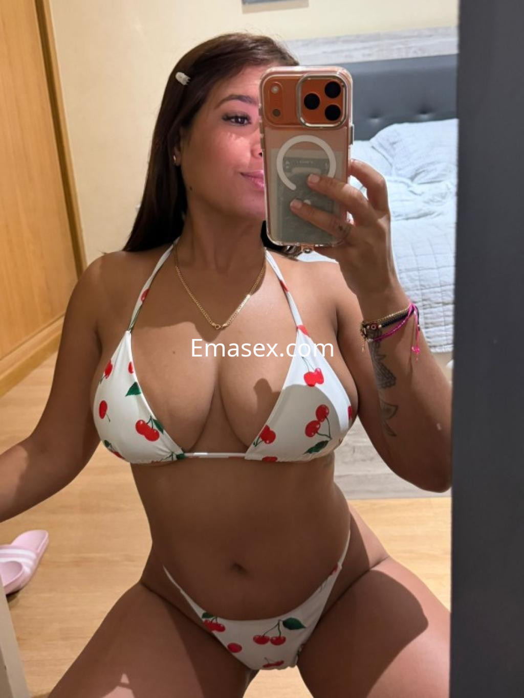 Escort en Ourense tomando una selfie frente al espejo, luciendo un bikini blanco con estampado de cerezas.