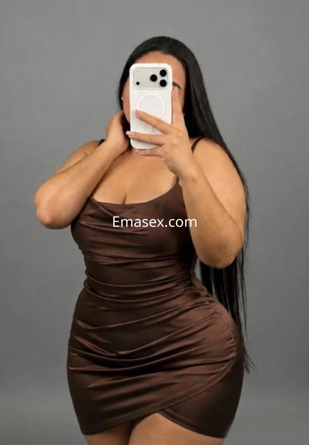 La puta luce un vestido marrón ajustado y tiene el cabello largo, posando frente a un fondo gris en Logroño.