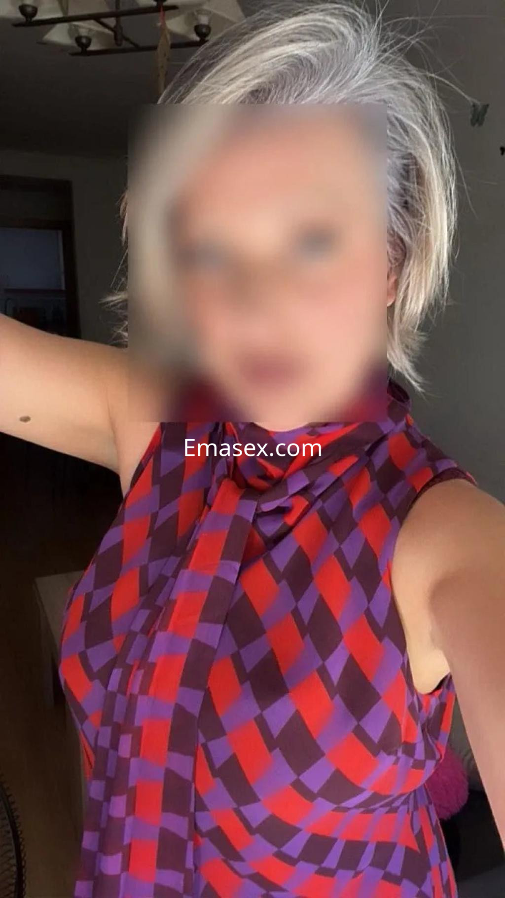 La puta posa con una blusa de cuadros rojos y morados en un ambiente interior de Toledo.