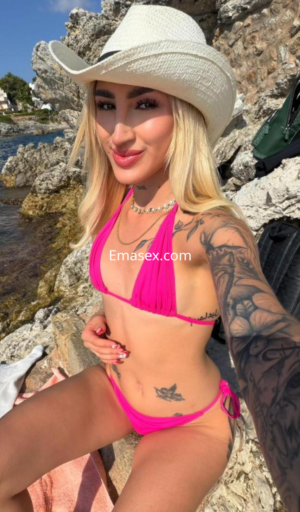 La puta luce un bikini rosa y un sombrero de vaquero, posando sonriente junto al mar en Granada.