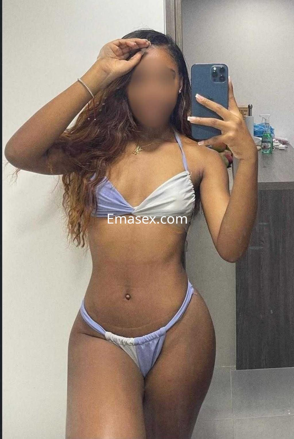 Escort en Huelva posando en un espejo, lleva un bikini de dos tonos y tiene el cabello largo y ondulado.