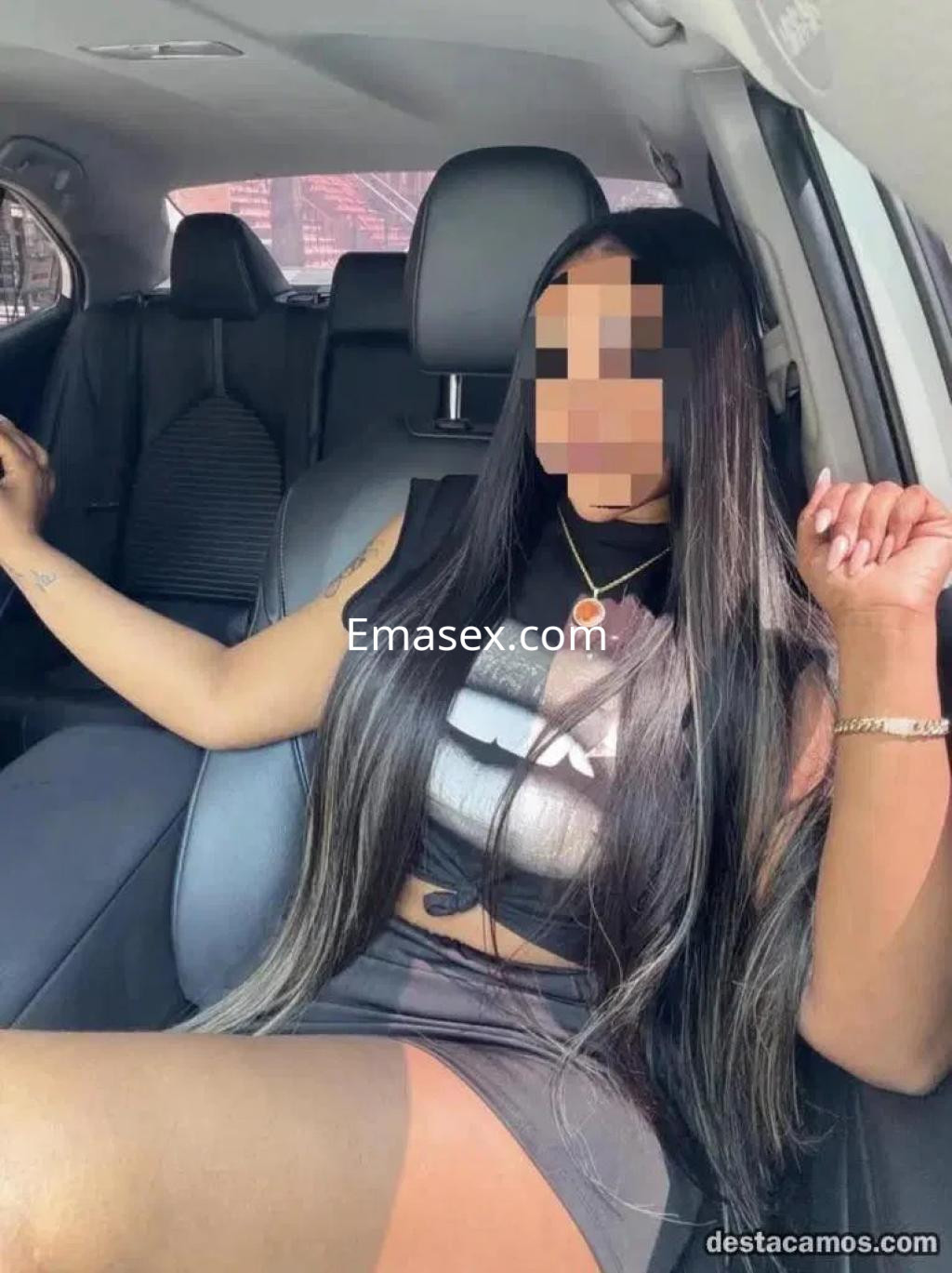 Puta en Valladolid lleva un top negro ajustado y una falda corta, posando en el interior de un coche.