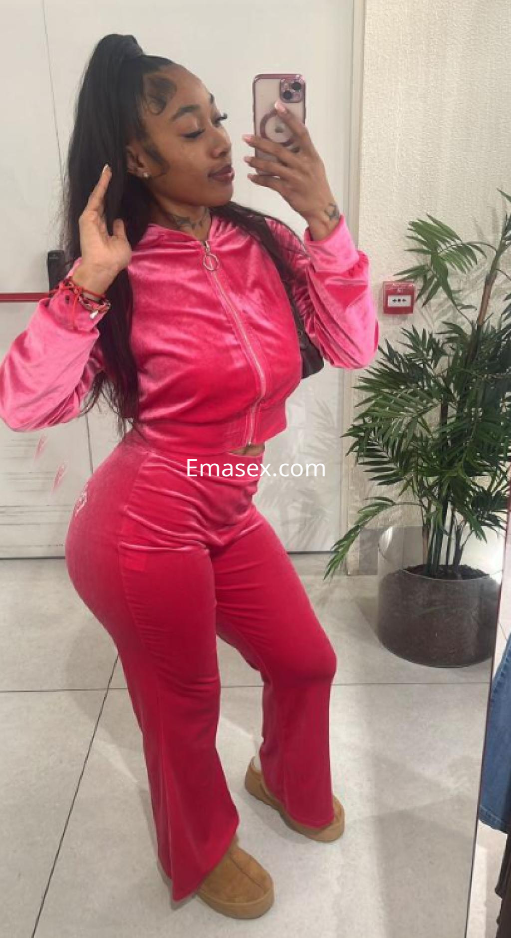 Escort en Santander posando frente al espejo con un conjunto de chándal rosa y zapatillas cómodas.