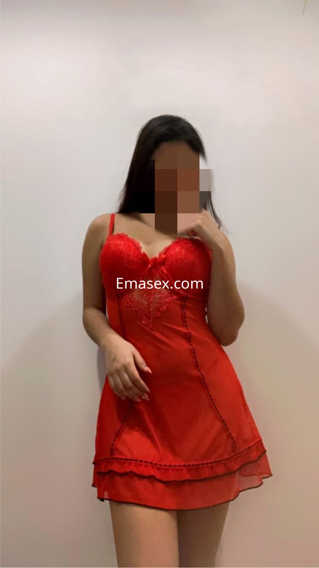 Escort en Murcia viste un vestido rojo transparente con delicados detalles, posando de forma seductora.