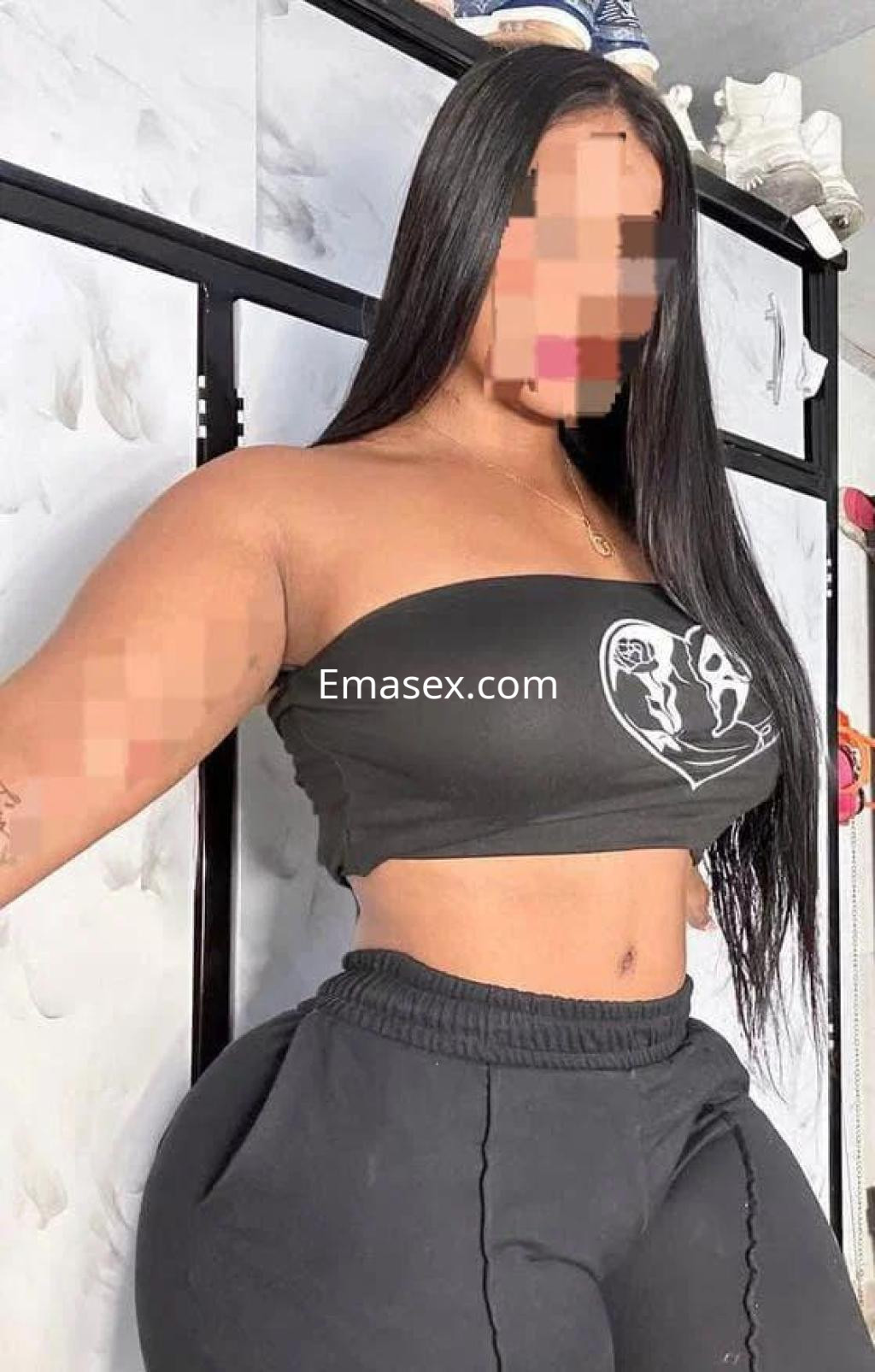 Escort en Madrid con cabello largo y lacio, vistiendo un top negro ajustado y pantalones deportivos oscuros.