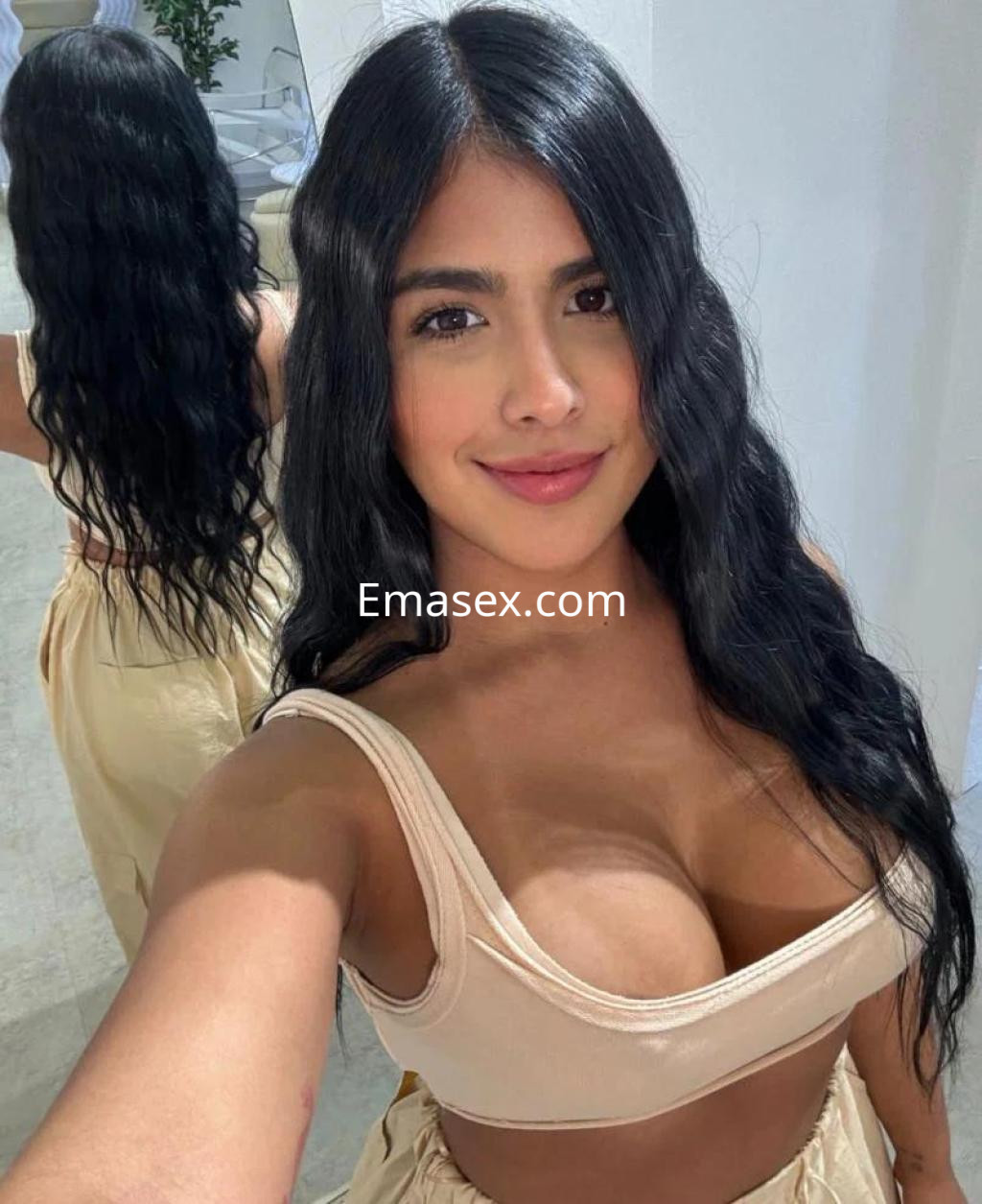 Puta con cabello largo y ondulado, viste un top beige y una falda clara, posando sonriente en Las Palmas.