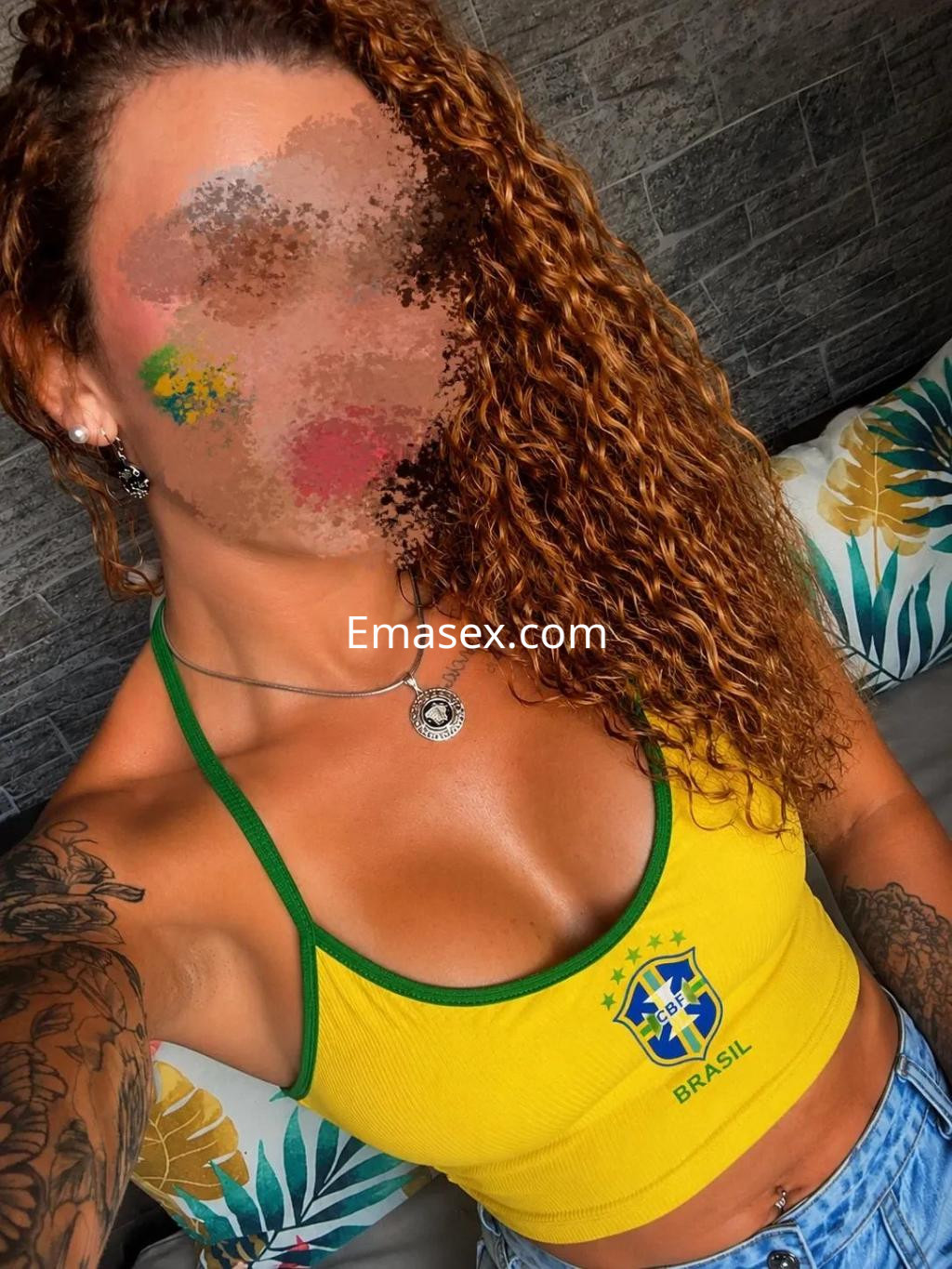 Puta con top amarillo de Brasil y jeans, posando en un ambiente interior con decoración tropical en Córdoba.