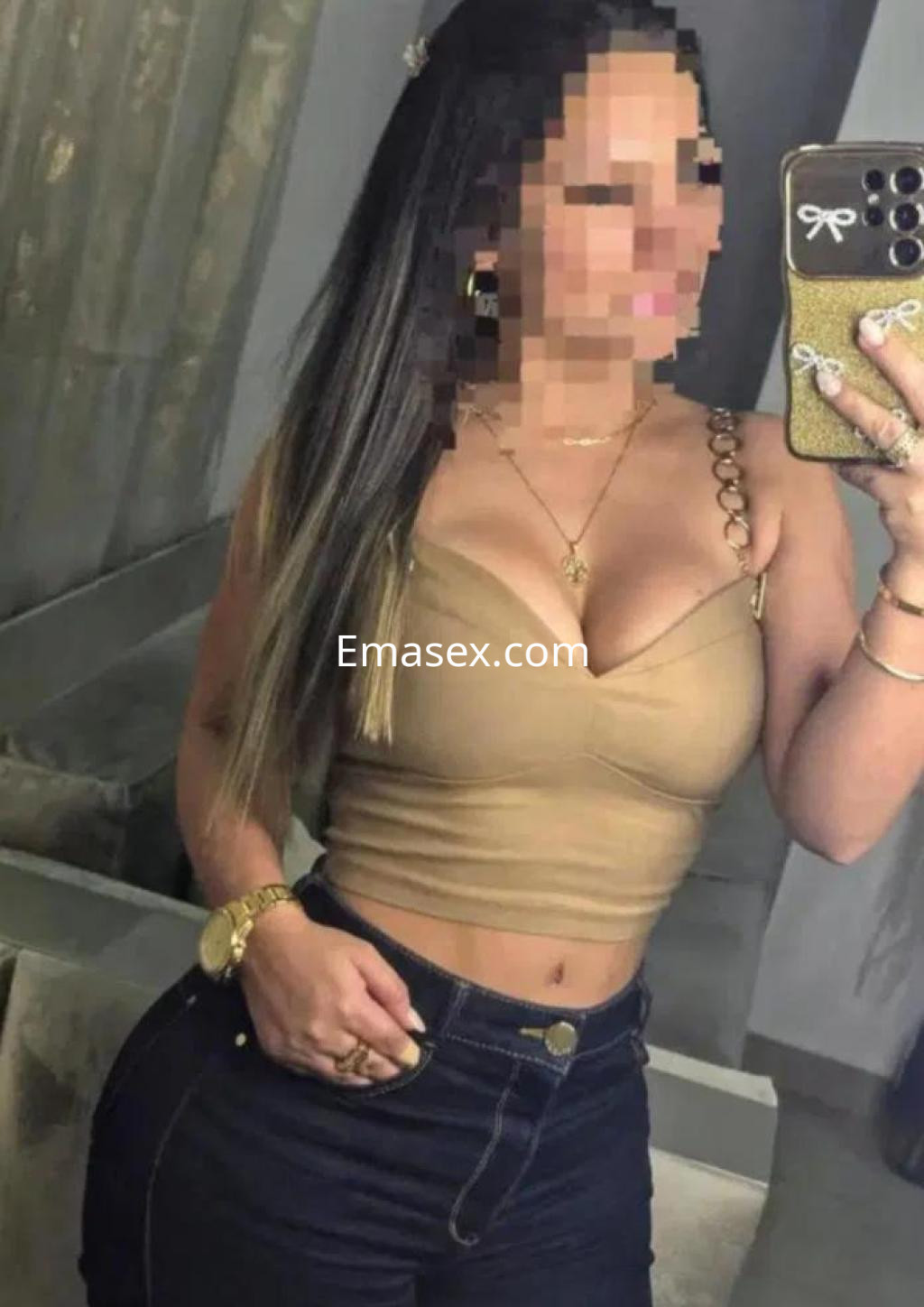 Escort en Córdoba con blusa beige ajustada y jeans oscuros, posando frente a un espejo.