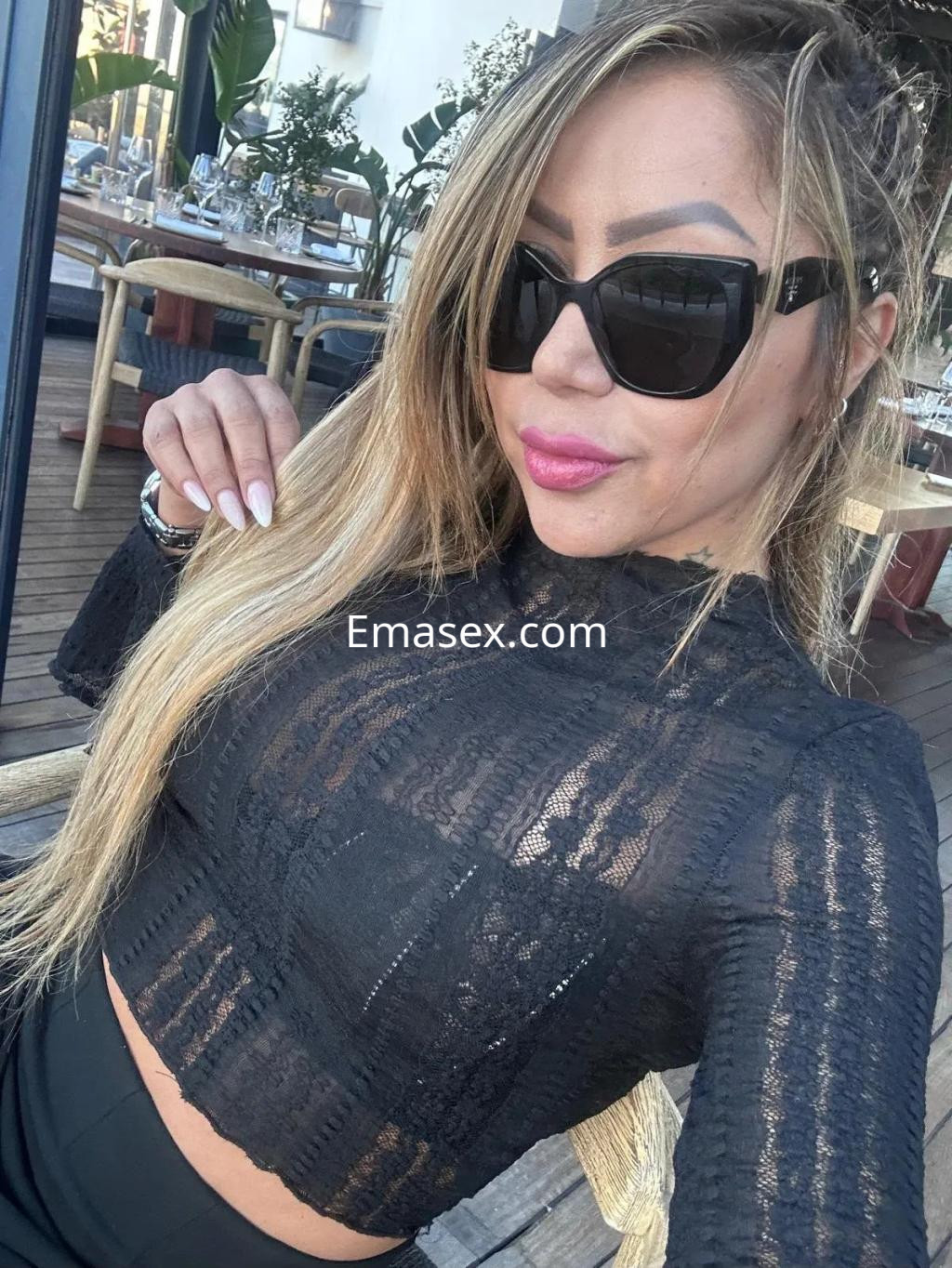 Puta con blusa negra de encaje y gafas de sol posando en un ambiente al aire libre en Palma de Mallorca.