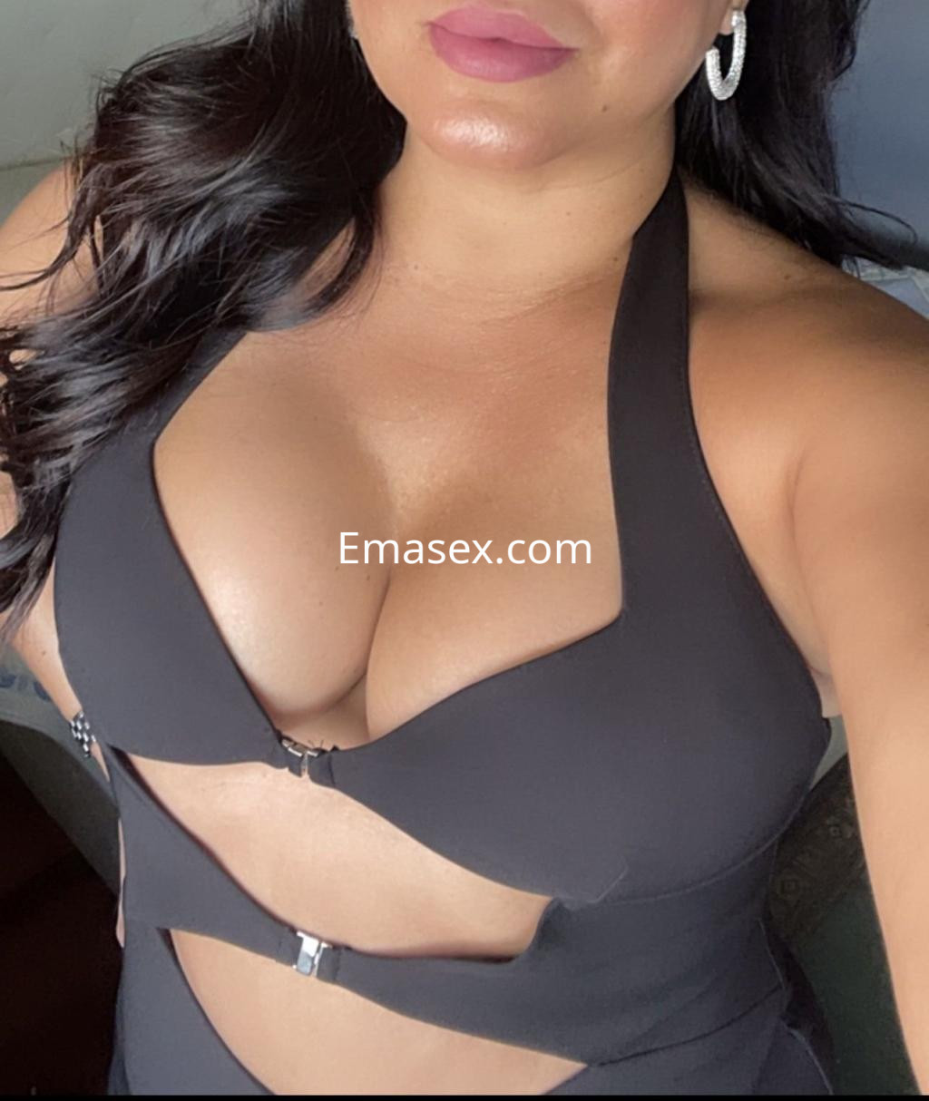 Puta en Toledo con un vestido negro ajustado que resalta su figura y pendientes brillantes.