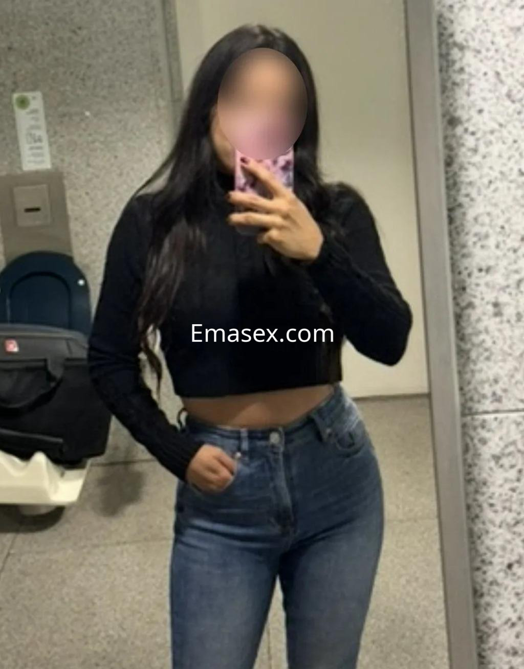 La escort se toma una selfie en un baño, luciendo un top negro y jeans ajustados, en Santander.