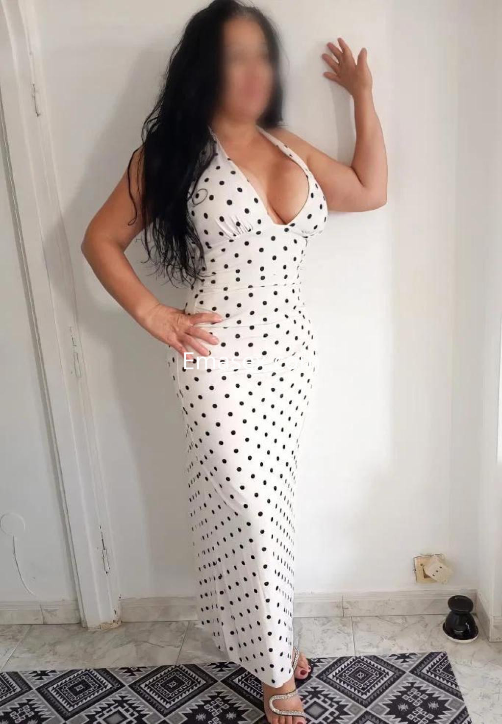 Puta en Las Palmas con vestido largo blanco de lunares negros, posando de pie y mostrando su figura.